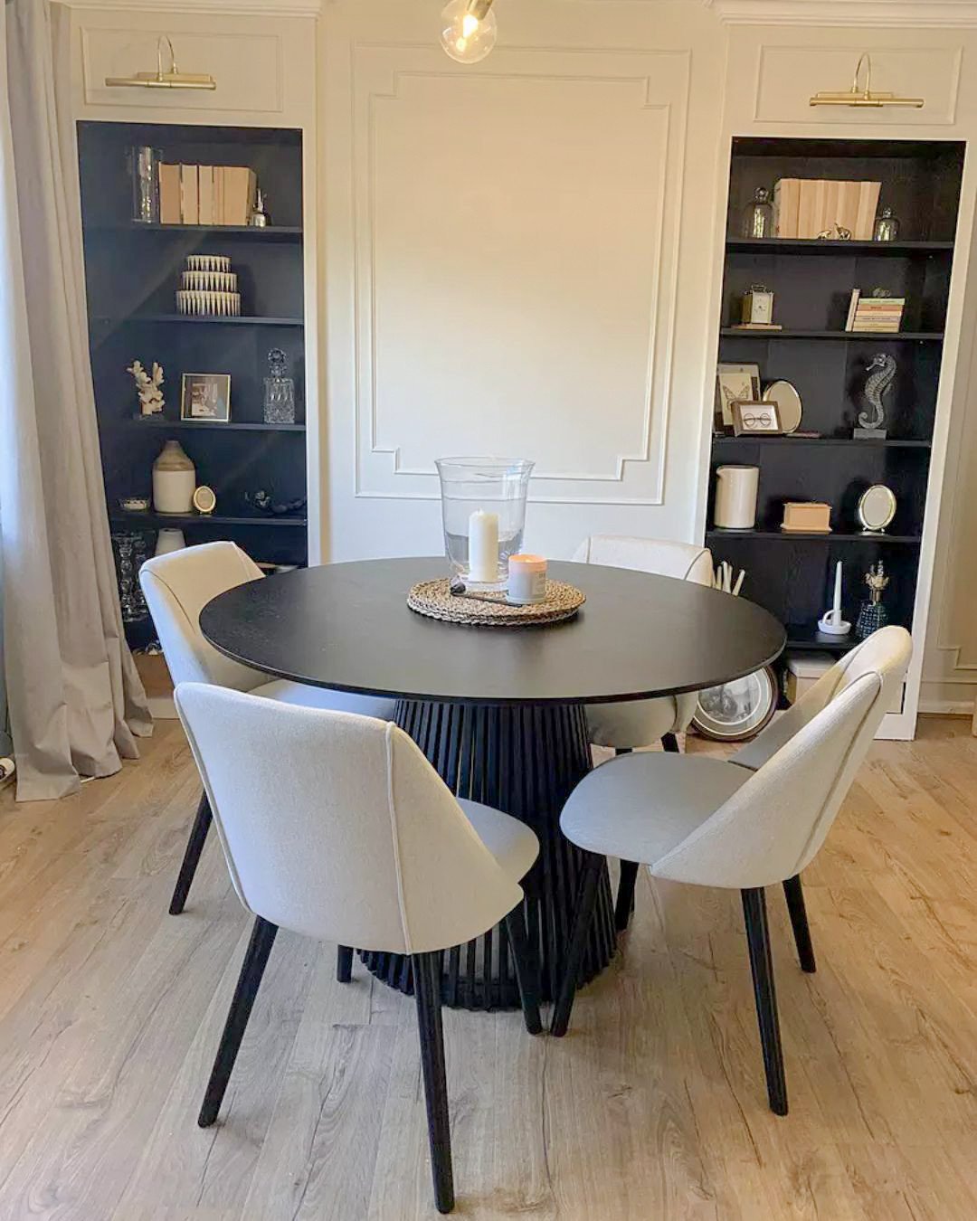 Round black dining table with fluted cone base and white chairs