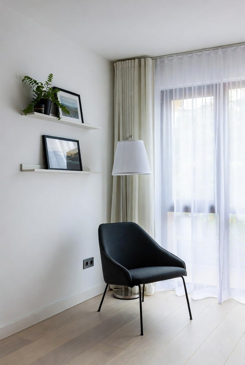 Two white floating picture shelves with black frames above a black chair