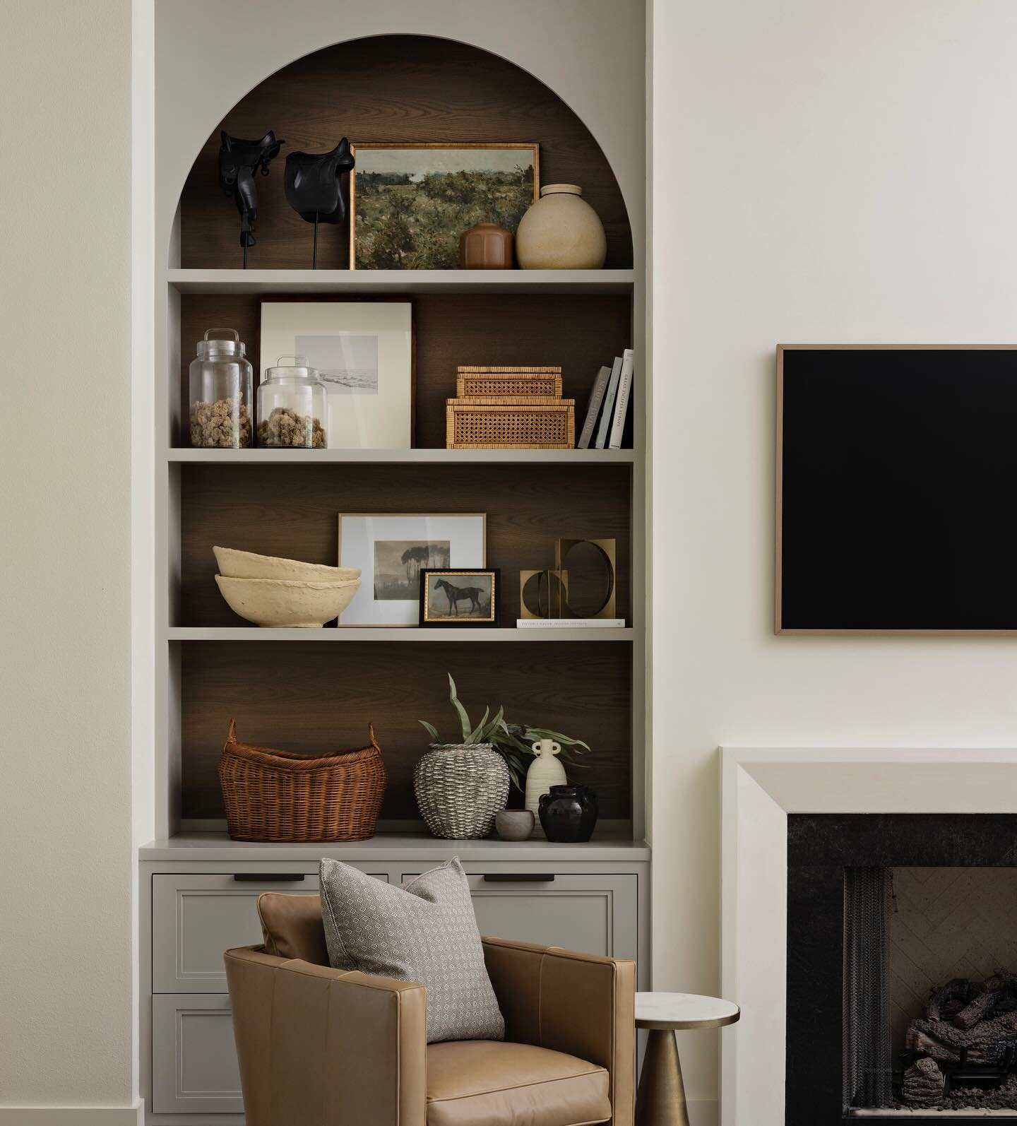 Arched built-in shelves with grey paint and dark wood backing styled with vintage decor