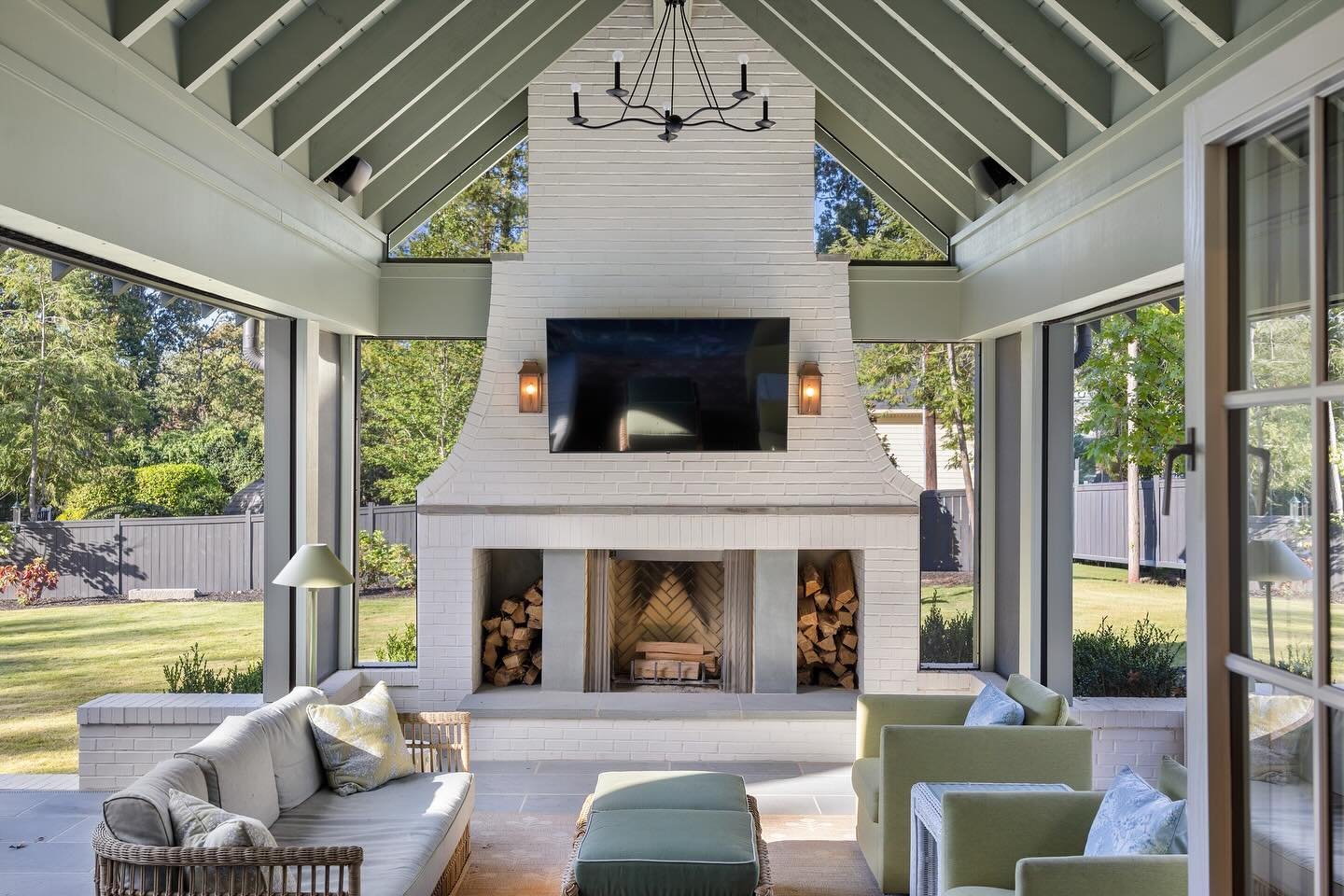 A large, white painted brick outdoor fireplace with integrated log storage niches and a gently curved lower mantle.