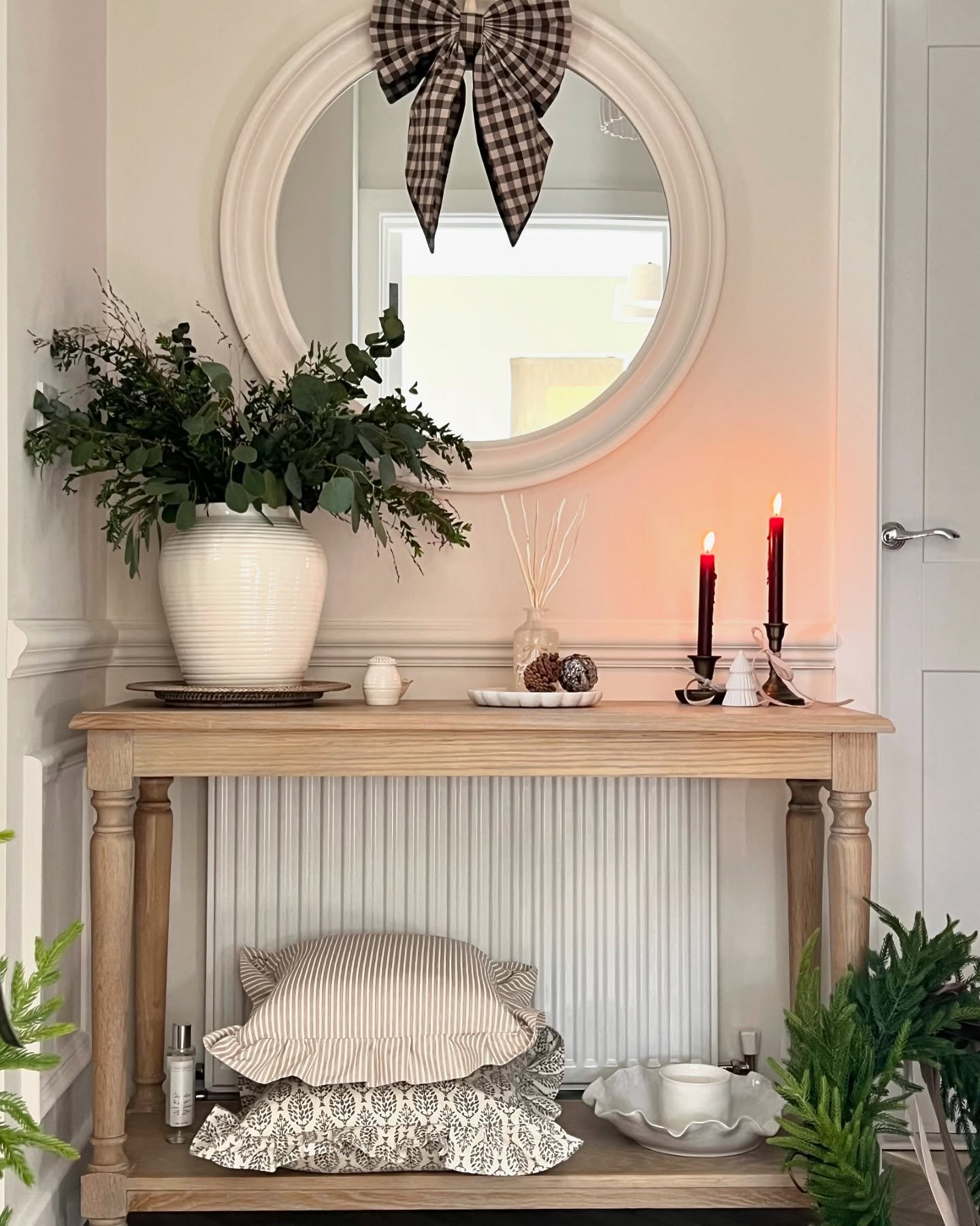 Wooden hallway table placed over radiator with candles and greenery