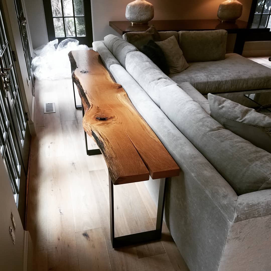Rustic live edge wood console table with black metal legs behind grey sofa