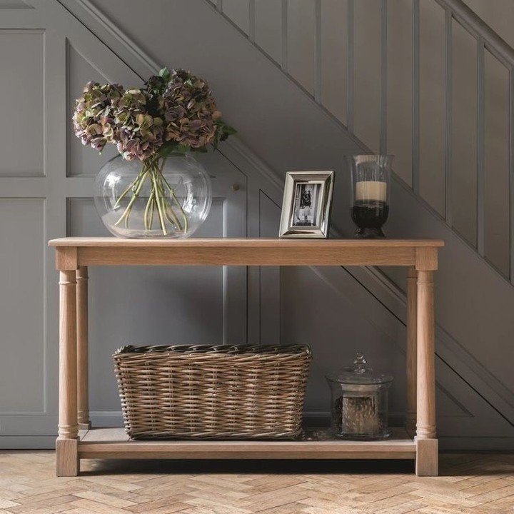 Light wood hallway table against grey paneling with hydrangeas