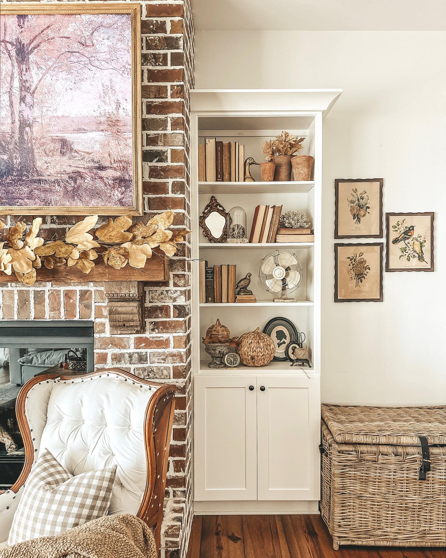White built-in farmhouse bookcase next to a brick fireplace styled with vintage decor