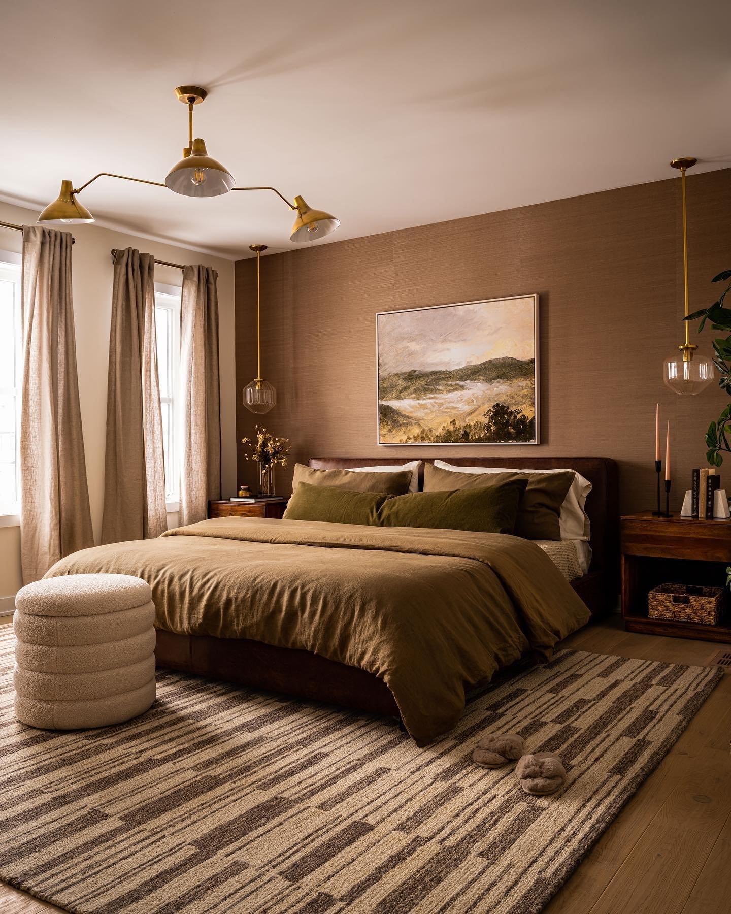 Brown bedroom featuring grasscloth wallpaper, gold chandelier, striped rug, and olive green bedding