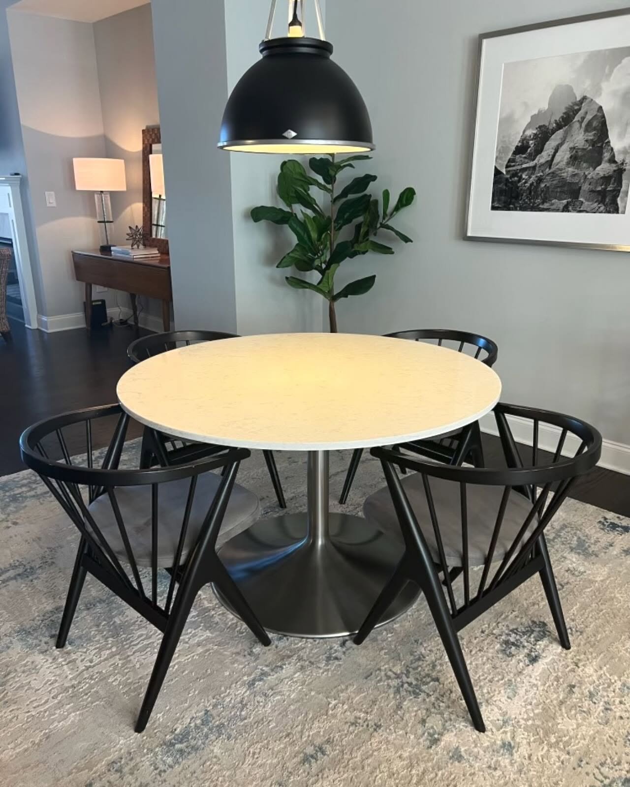 Round white stone kitchen table with silver metal tulip base and black chairs
