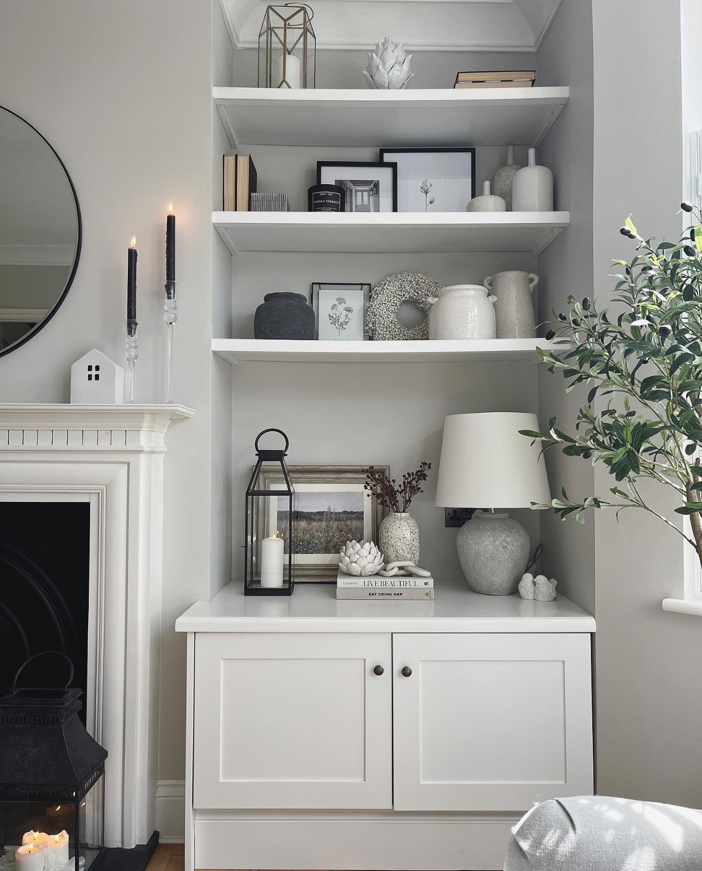 White built-in shelves and cabinet in a grey living room alcove styled with neutral decor