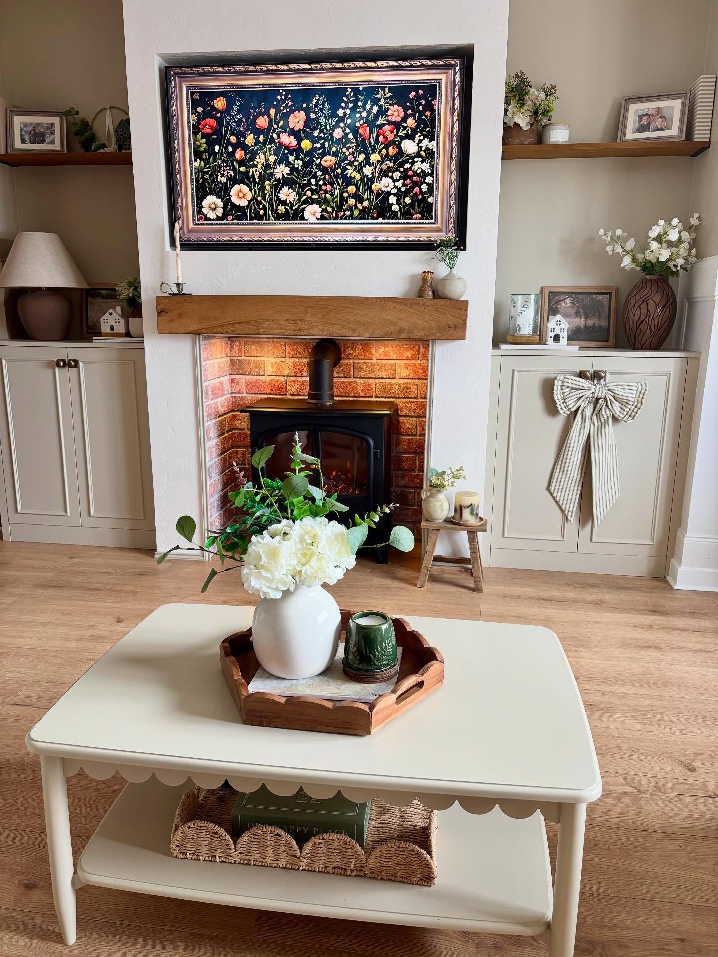 Beige built-in cabinets with a decorative bow and floral digital art above a brick fireplace.