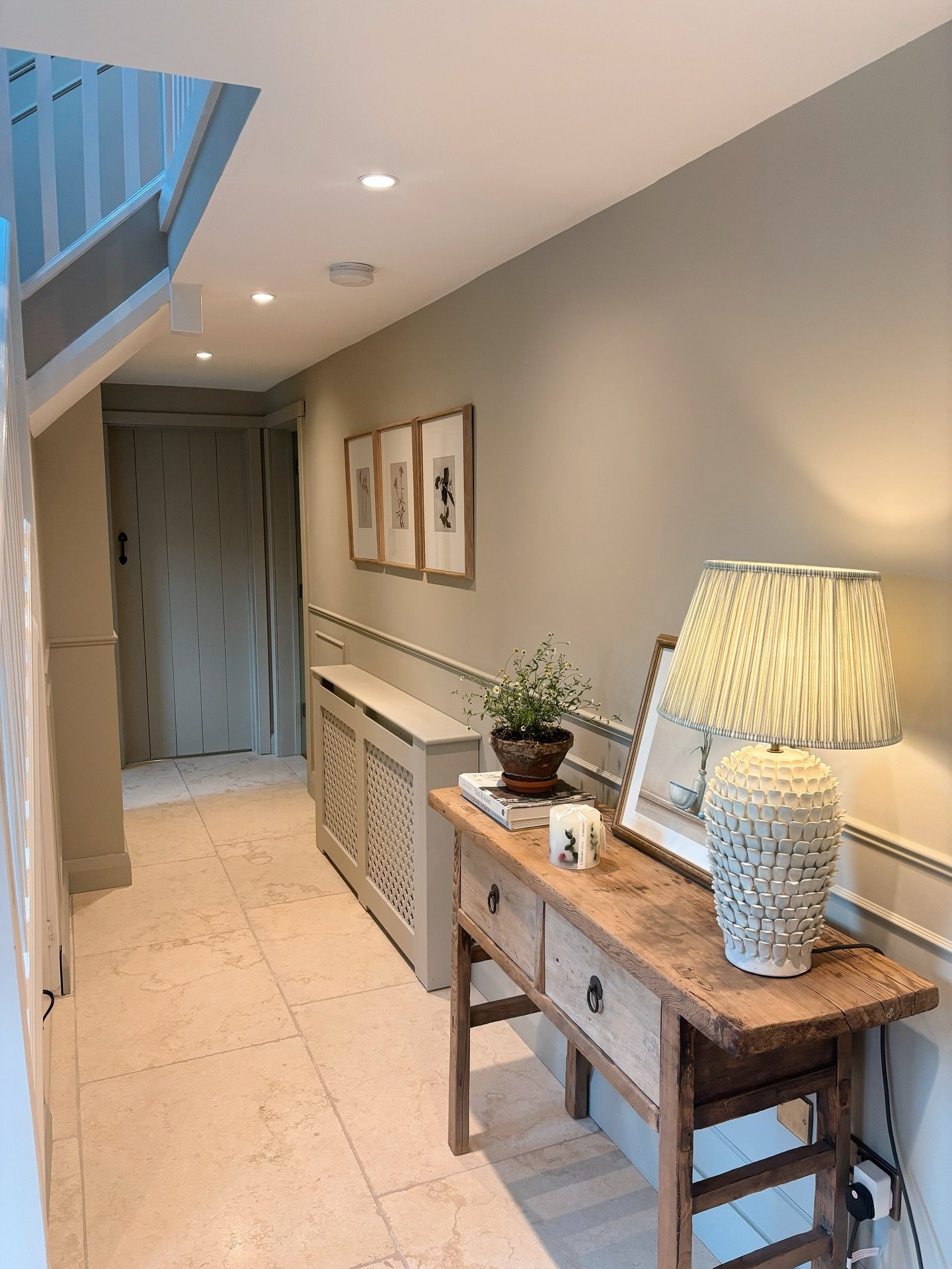 Rustic wooden hallway table with textured lamp and plant in narrow corridor