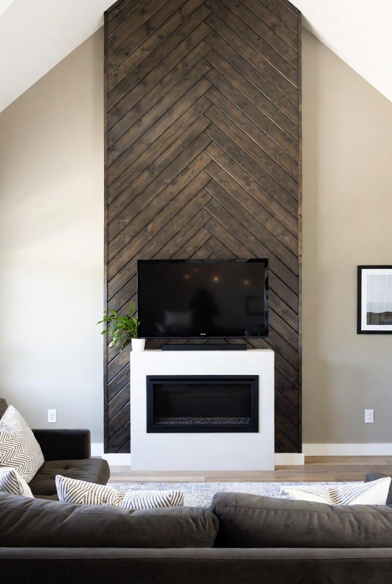 Dark stained wood chevron accent panel extending to a vaulted ceiling behind a fireplace