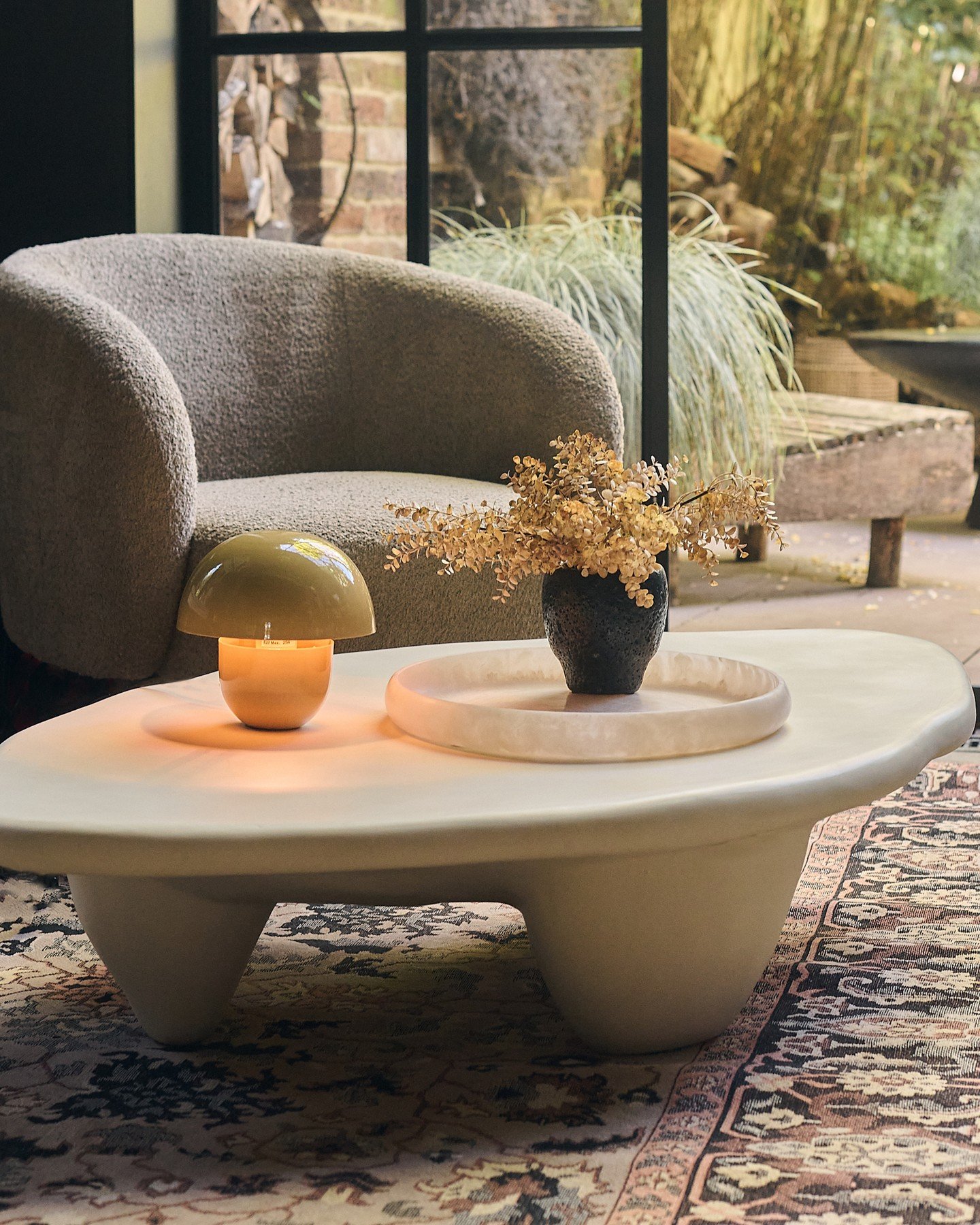 Cream organic shaped coffee table with chunky legs styled with a lamp