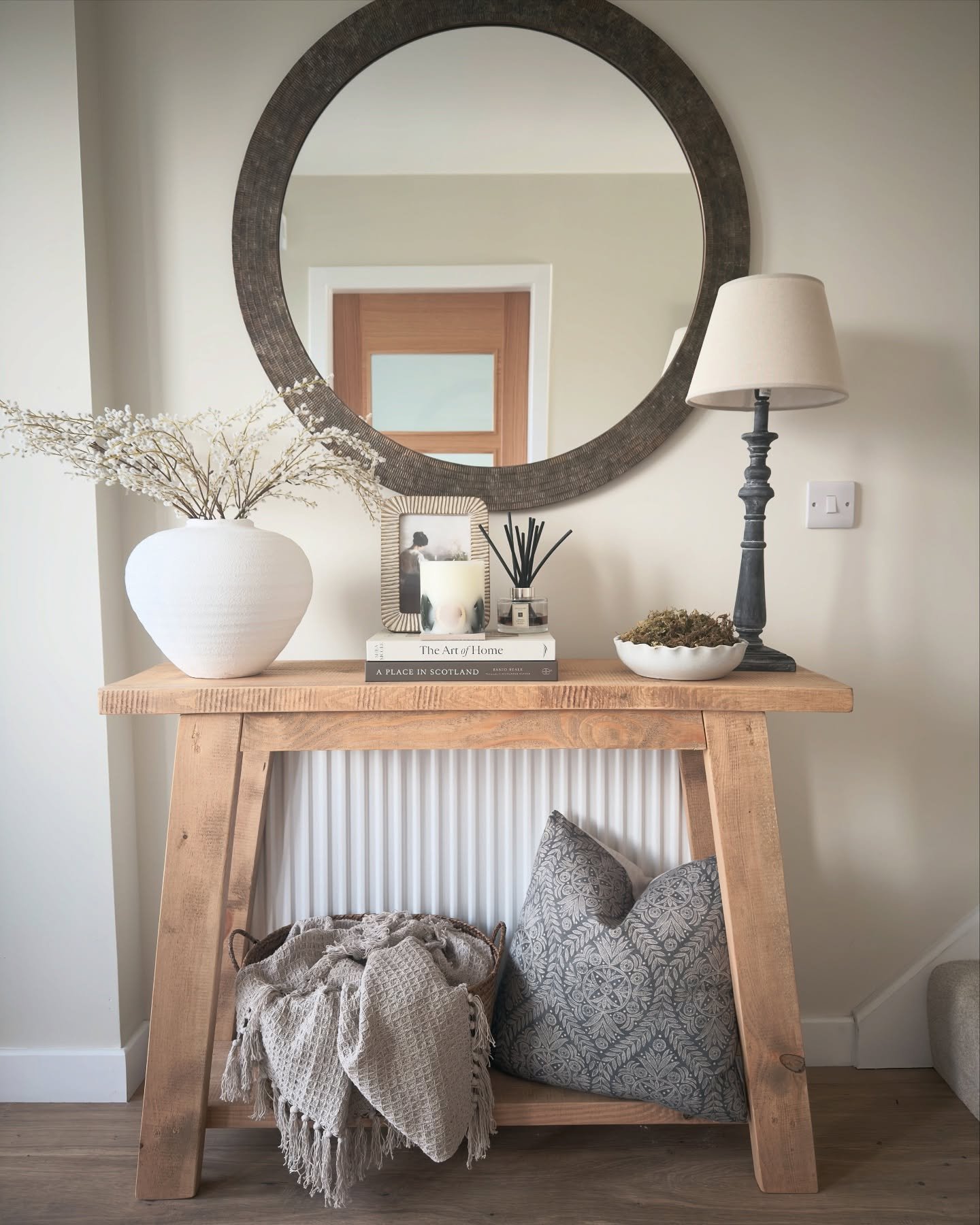 Chunky wooden hallway table over radiator with mirror and textiles