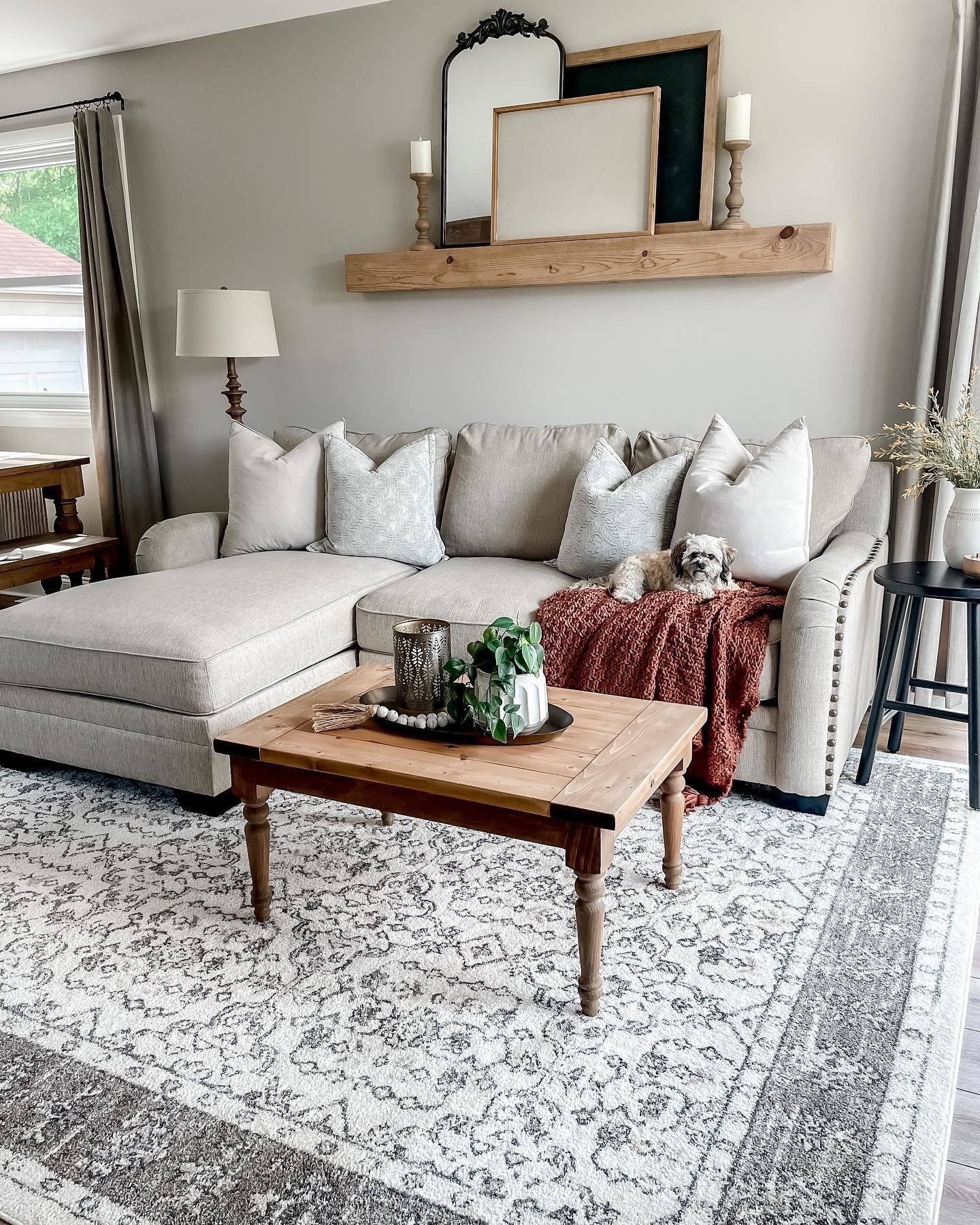 Thick wooden floating beam with leaning frames and mirror above beige couch