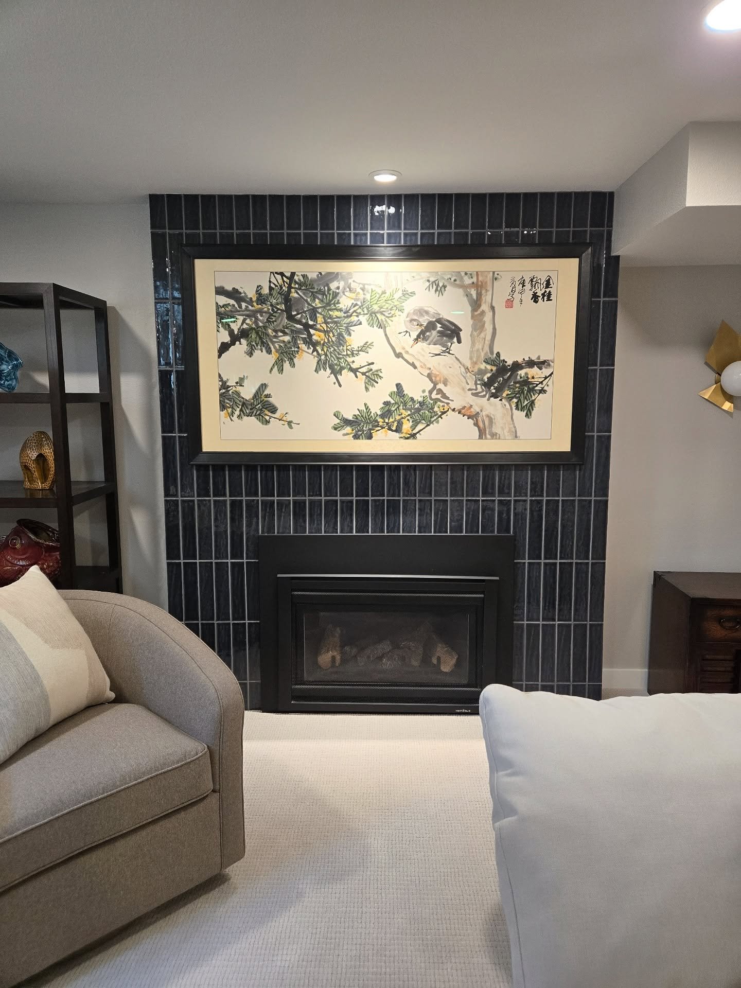 A contemporary fireplace featuring a floor-to-ceiling surround of dark, slim rectangular tiles installed in a vertical stacked pattern.