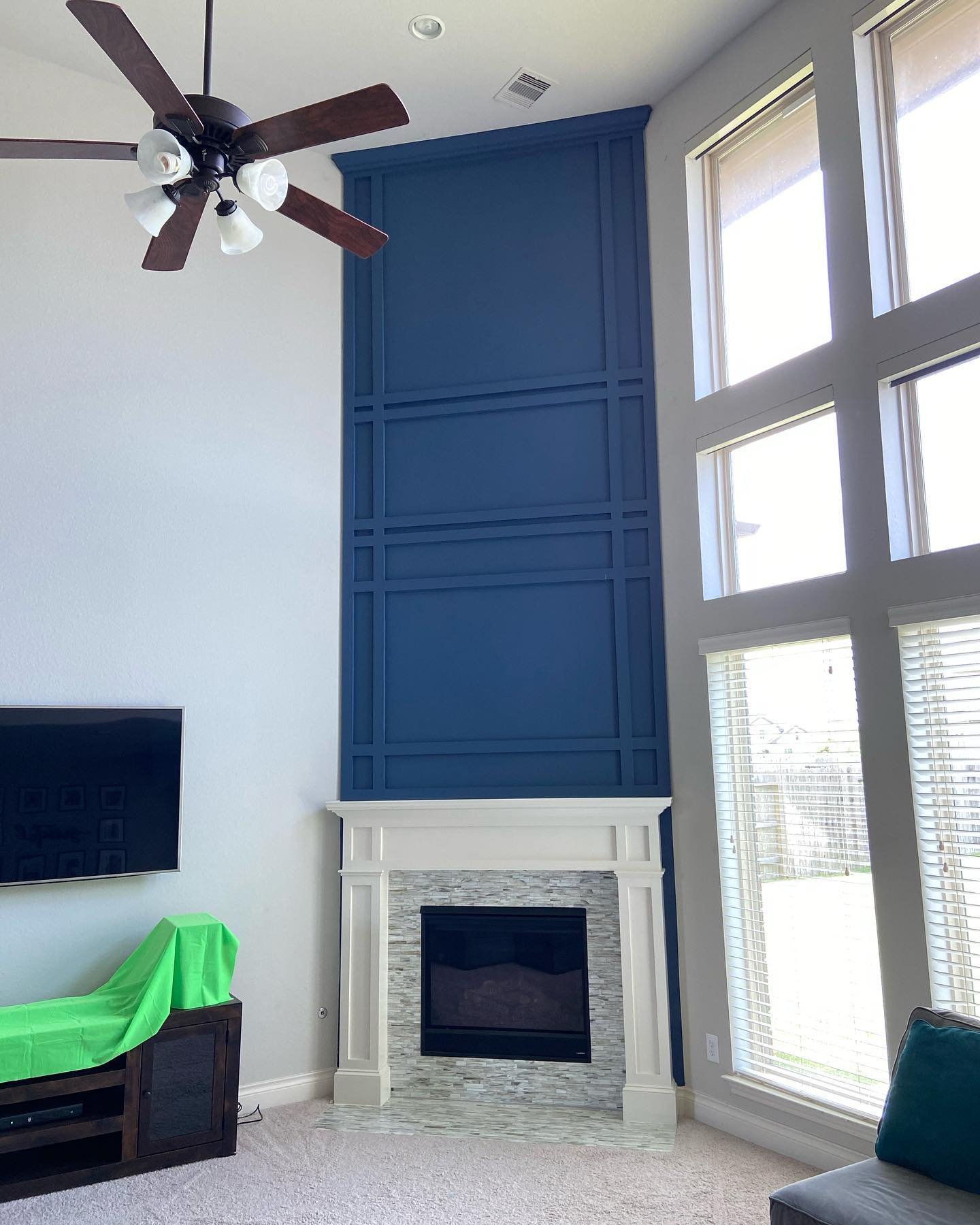 Vaulted living room with a fireplace accent wall painted a deep navy blue, featuring geometric wainscoting and a classic white mantel.