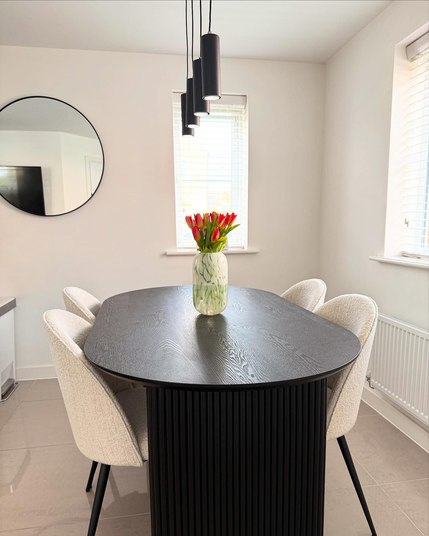 Oval black kitchen table with ribbed base and textured white chairs