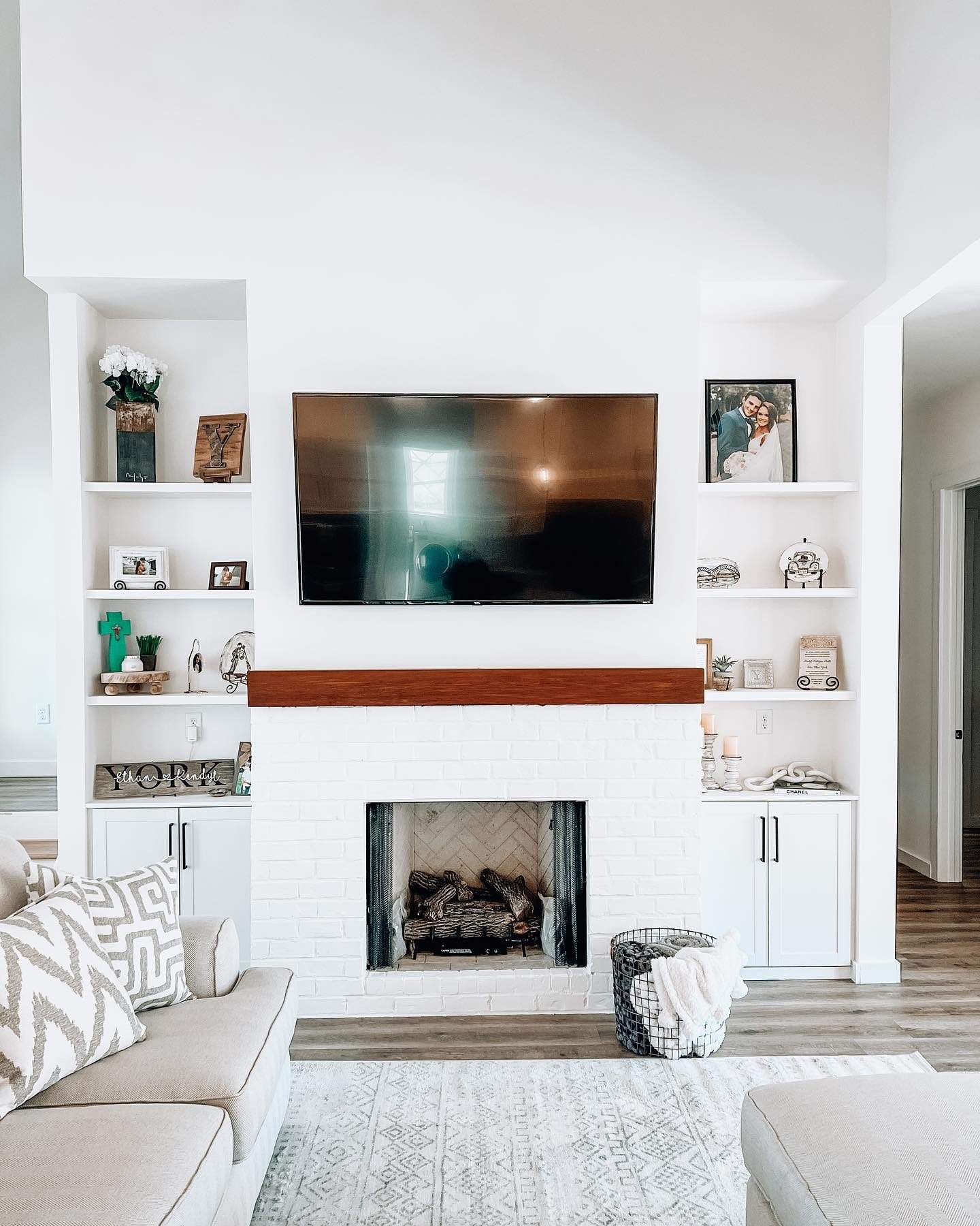 White recessed built-in shelves flanking a brick fireplace with black hardware