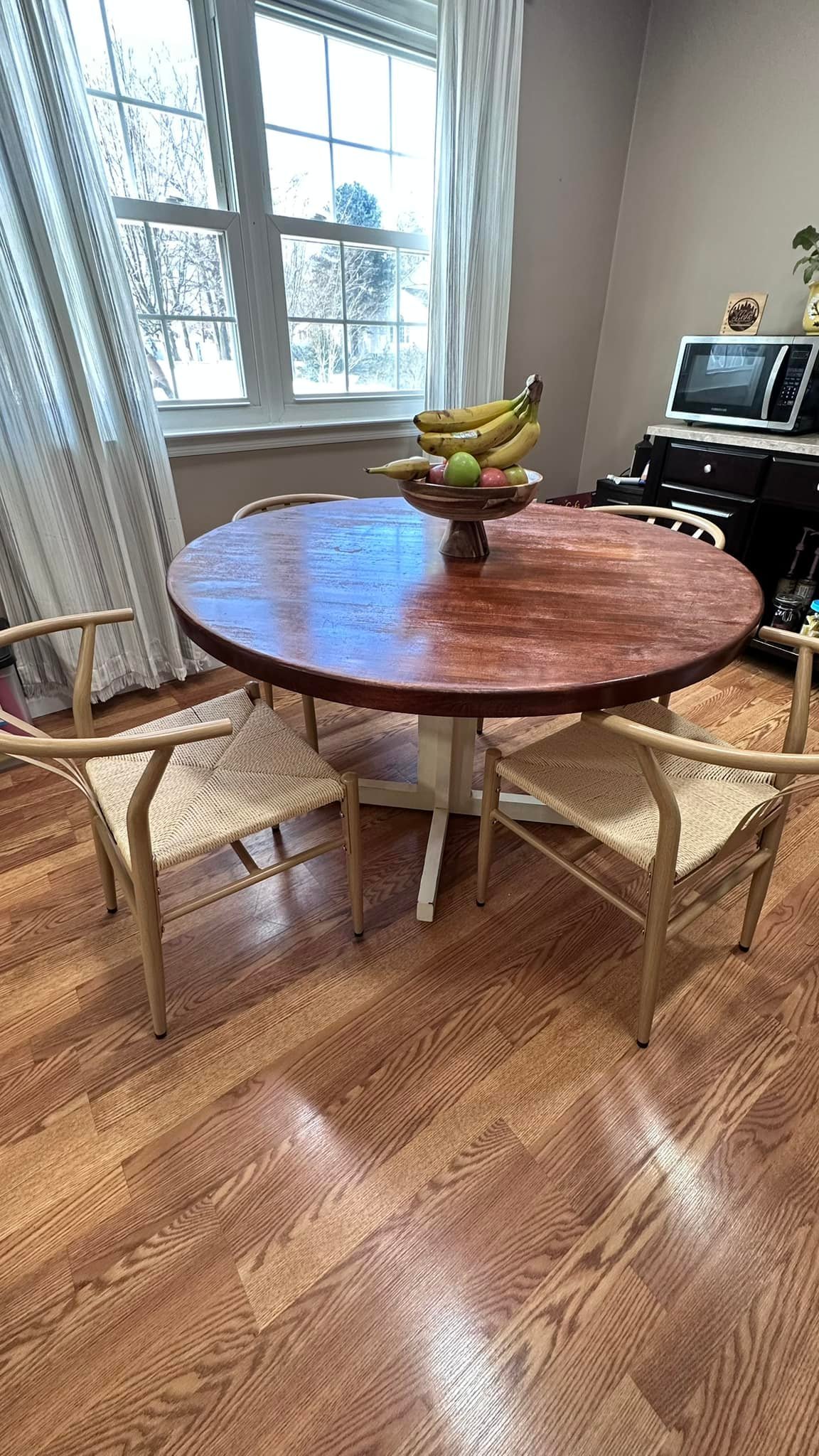 Round dark wood dining table with white base and wishbone chairs