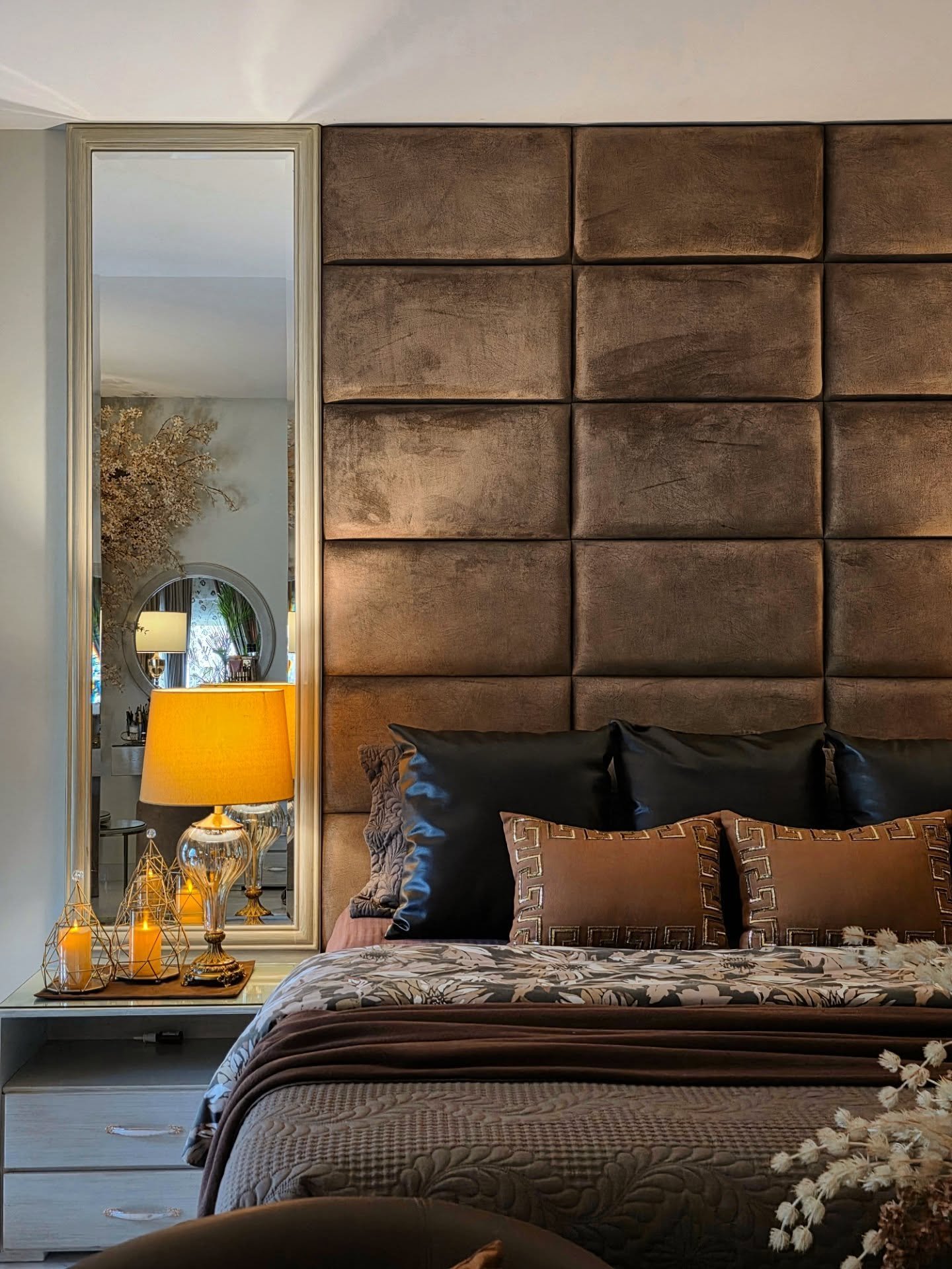 Bedroom featuring floor-to-ceiling brown velvet wall panels, a tall mirror, and luxurious bedding with leather accents