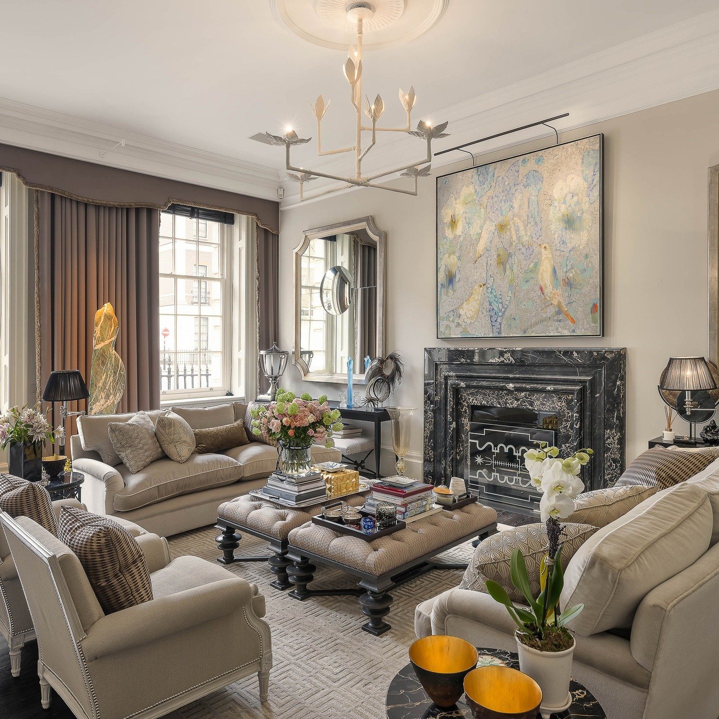 An elegant, traditional sitting room featuring a heavily veined black marble fireplace with a carved mantel and a decorative iron fire basket.