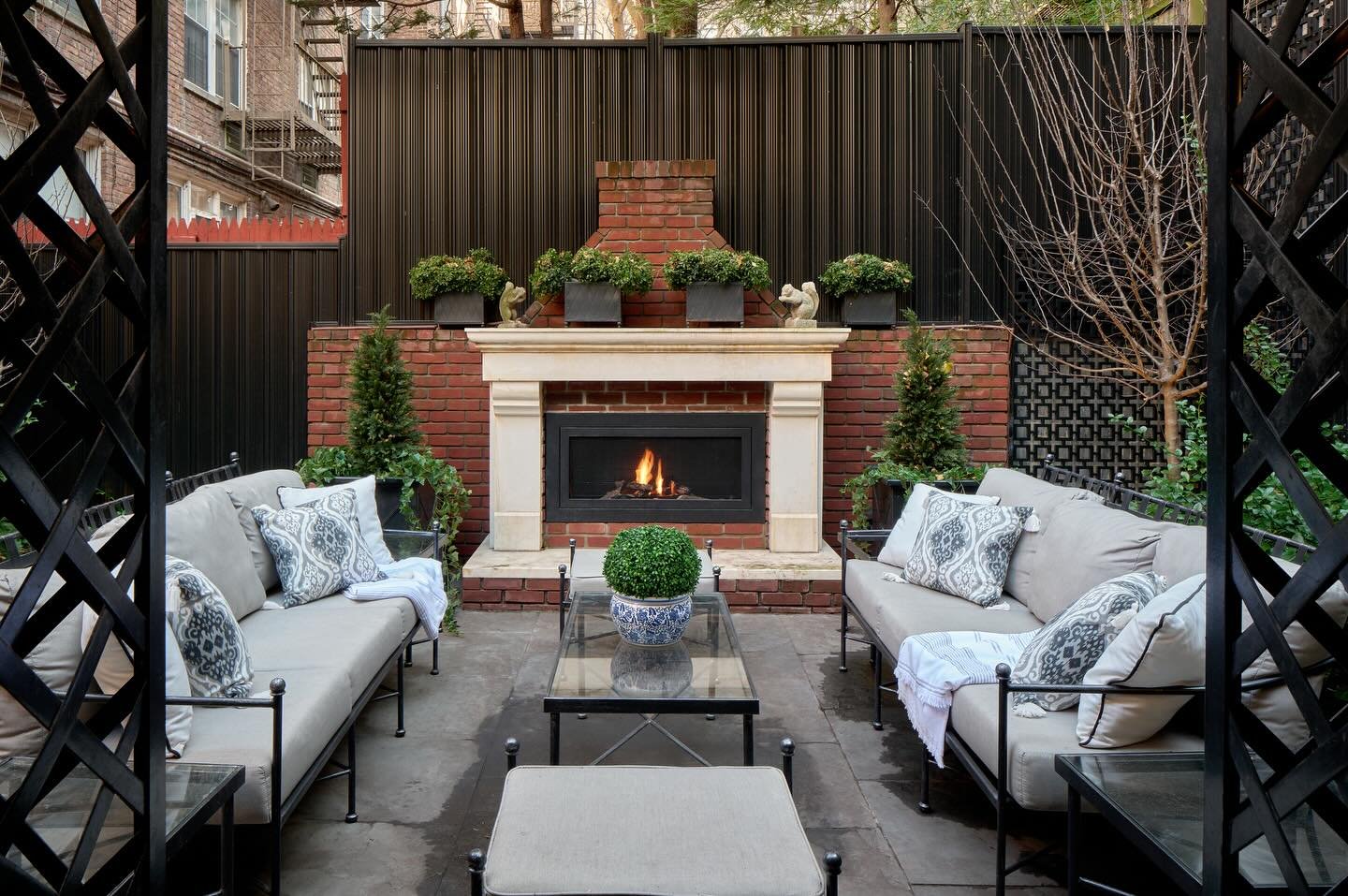 Traditional red brick outdoor fireplace with a classic, contrasting white stone mantelpiece in an urban patio setting.
