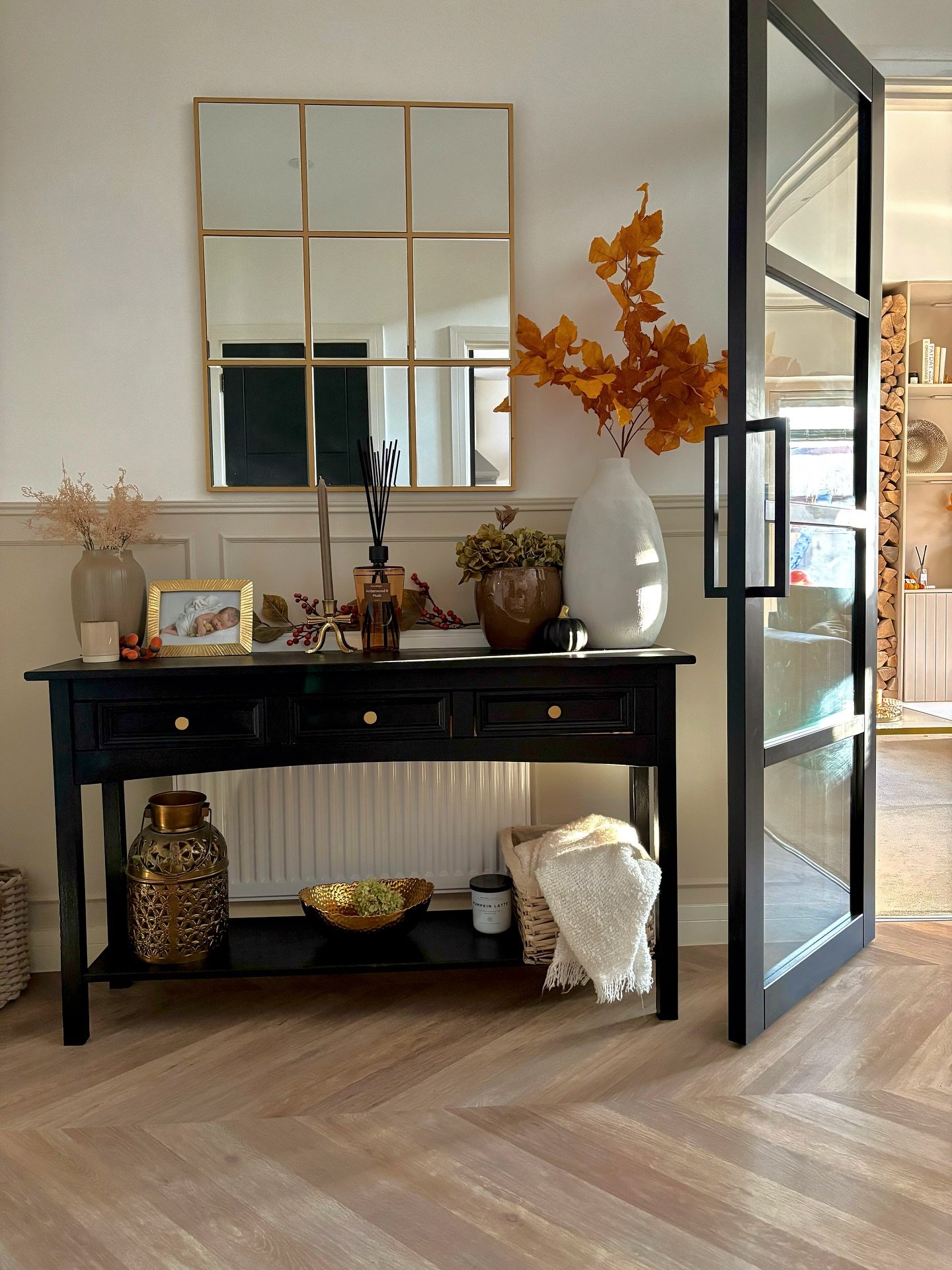 Black hallway table with gold mirror and autumn leaves