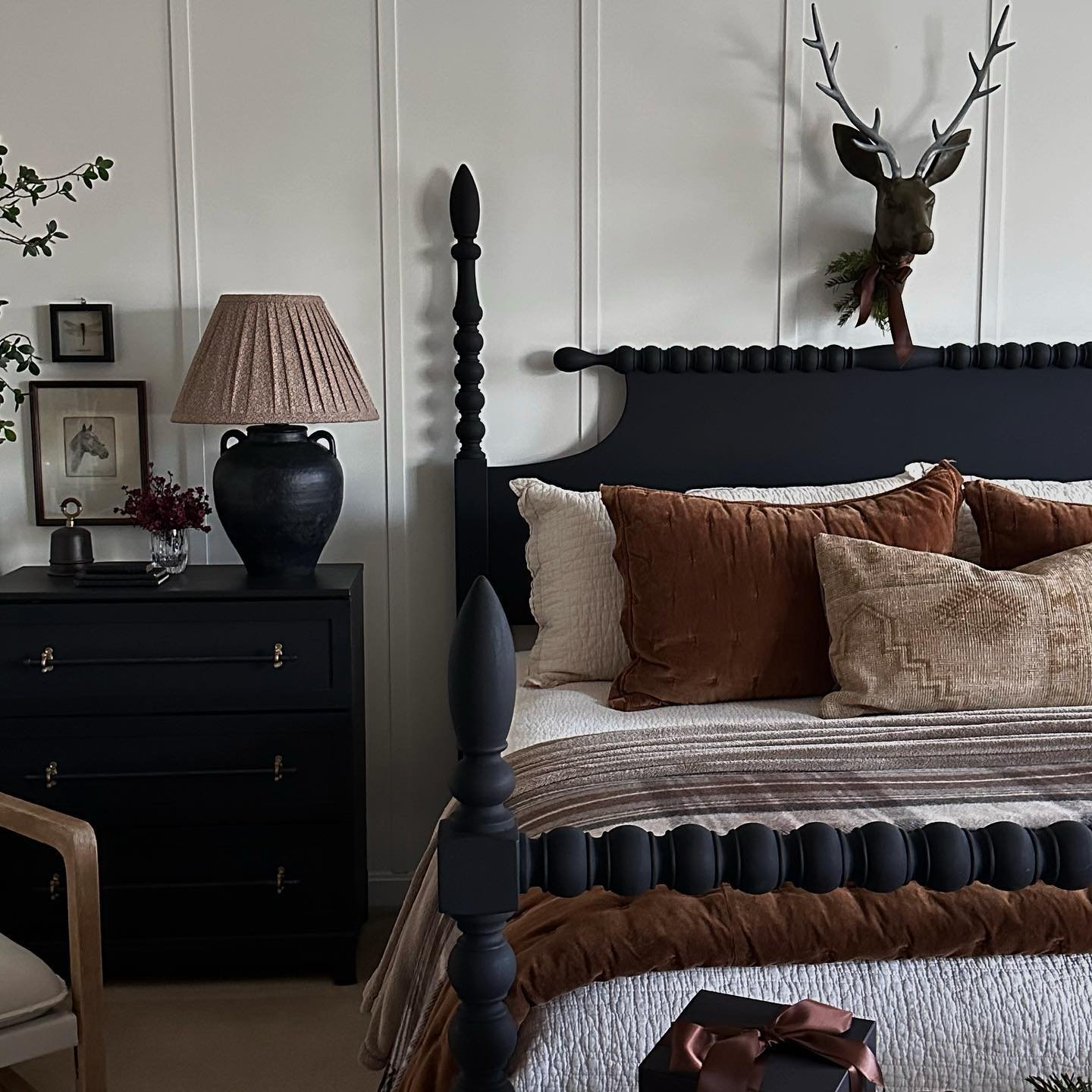 Black spindle bed with rust velvet pillows and deer wall decor