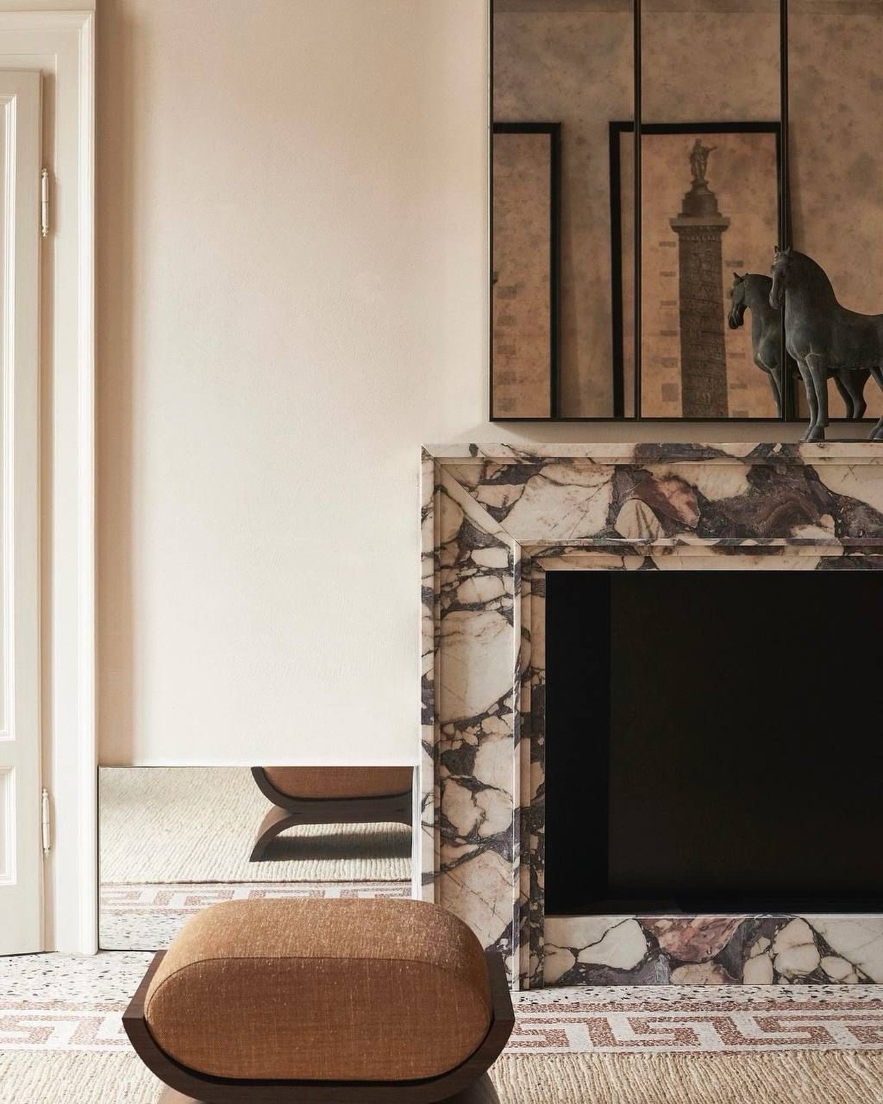 A detailed close-up of a fireplace surround made from white marble with very intense deep purple and reddish-brown veining, complemented by antique mirrored panels above.