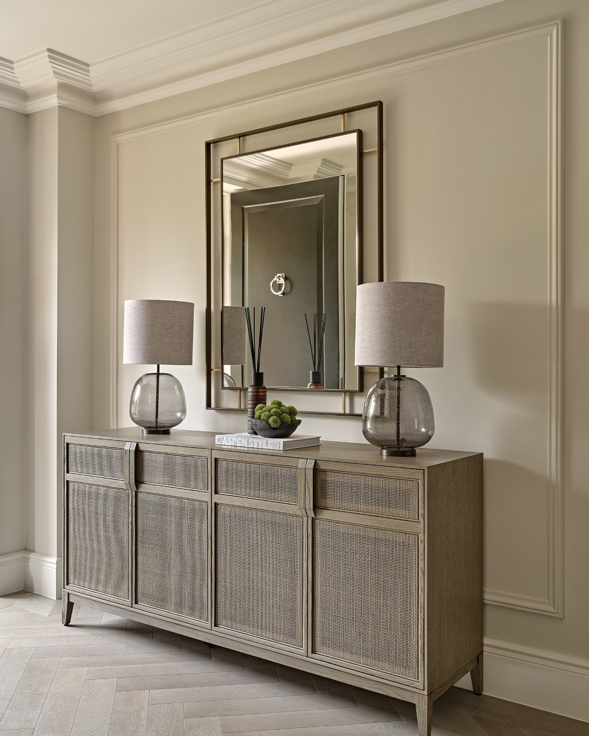 Long grey woven sideboard in hallway with symmetrical lamps and mirror