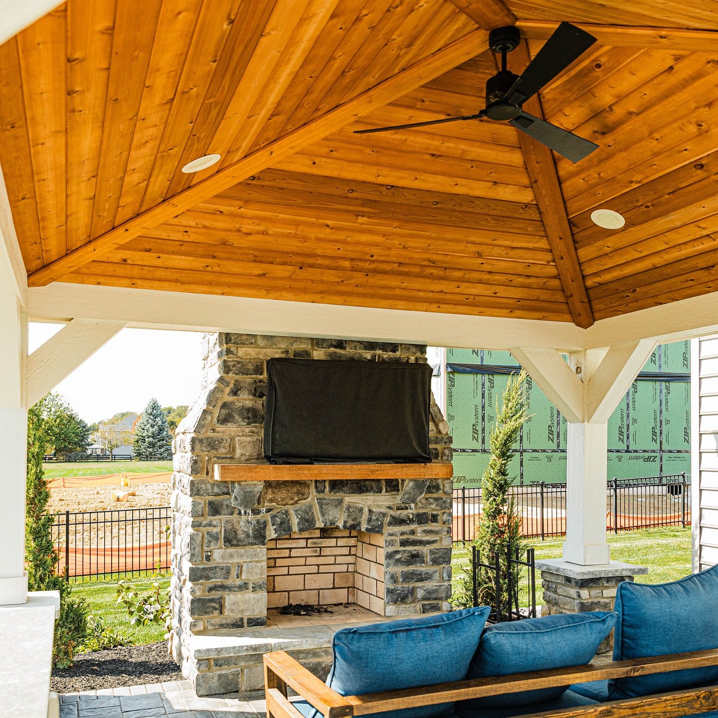 Traditional-style outdoor fireplace made with dark fieldstone and featuring a subtle arched firebox opening and light brick interior.