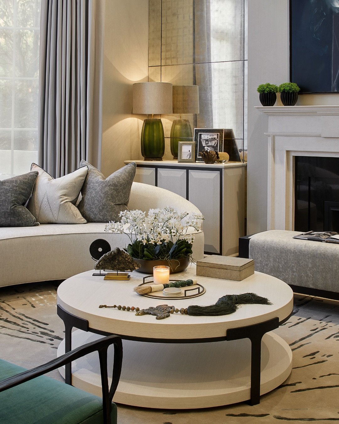 Round light wood coffee table with dark metal frame and lower shelf styled with decor