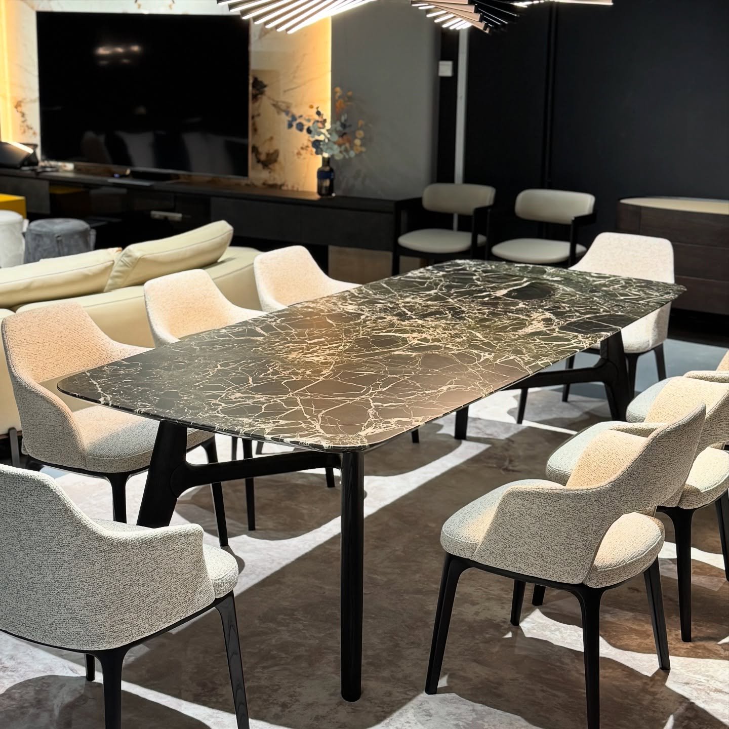 Rectangular black marble dining table with cream upholstered chairs in modern living space