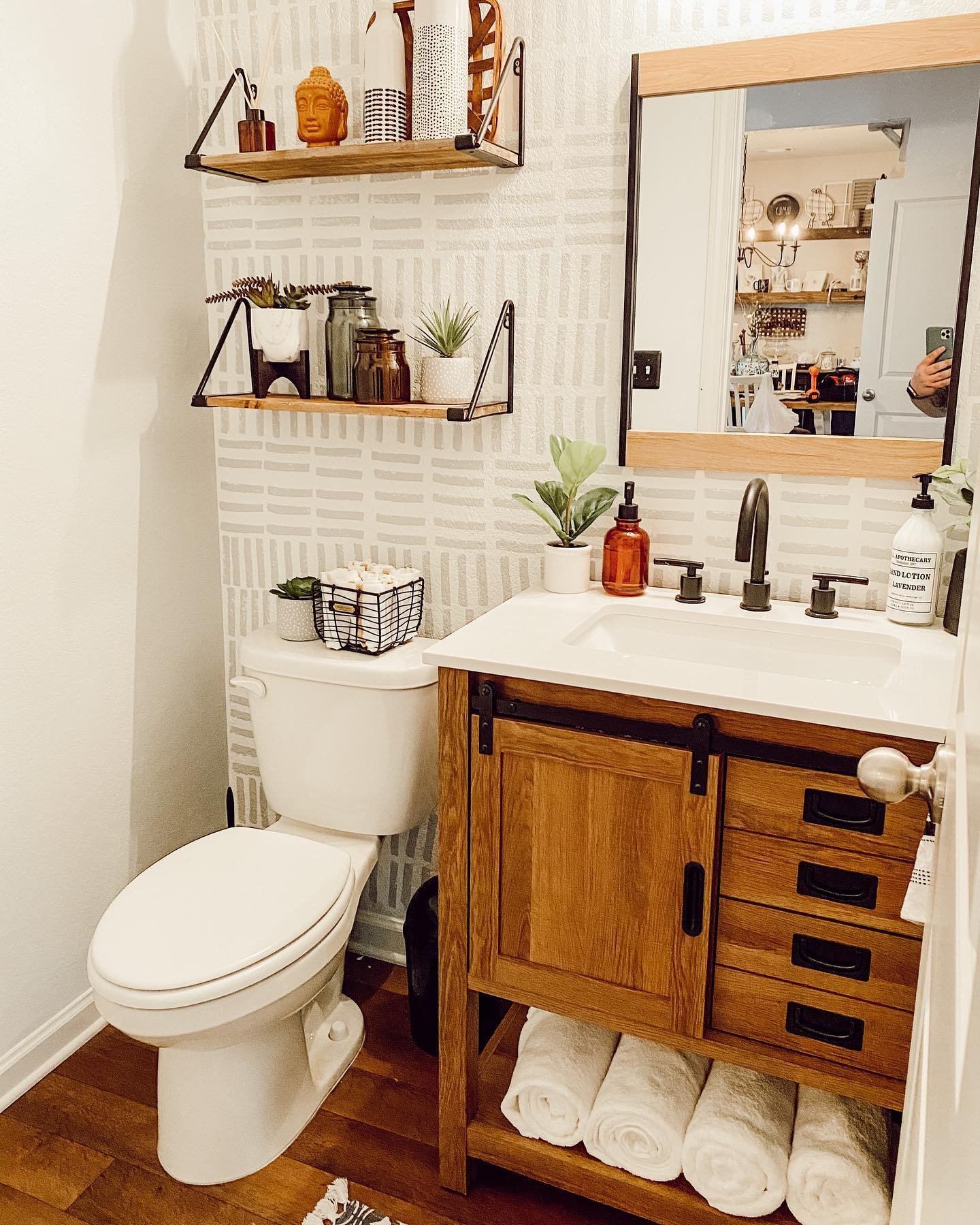 Two wood shelves with black triangular wire brackets mounted on patterned wallpaper