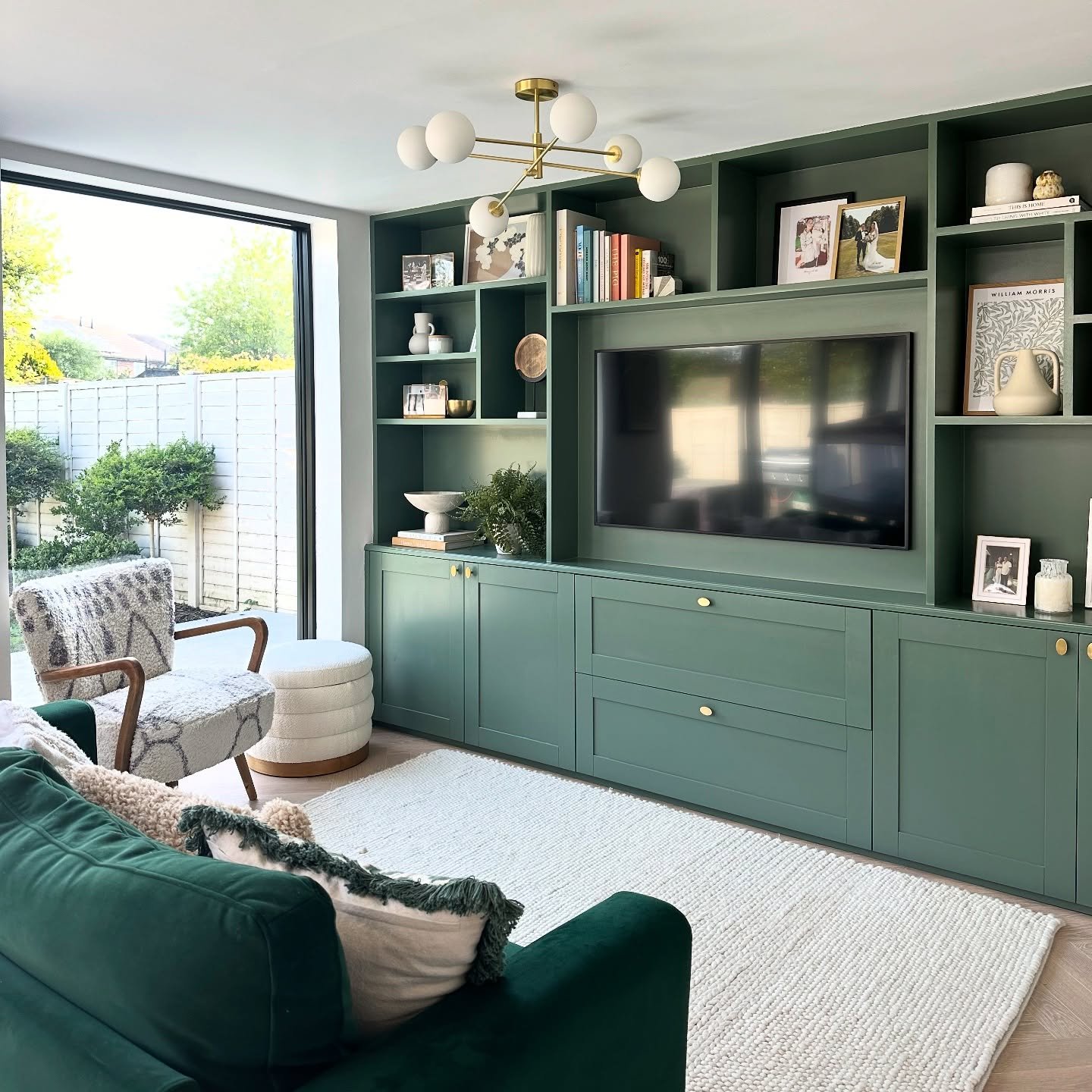 Green wall-to-wall built-in media unit with cubby shelves and brass hardwareDeep forest green lacquer engulfs the massive wall unit for a bold impact. Asymmetri