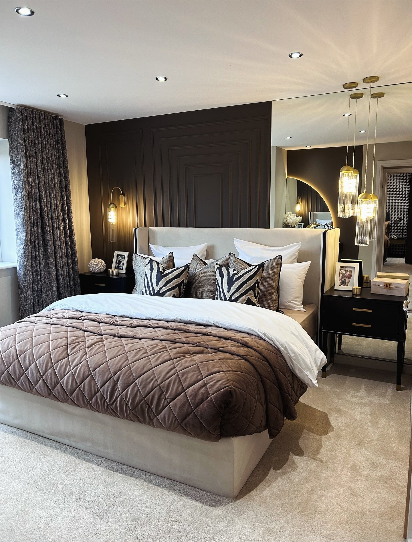 Brown bedroom featuring a geometric paneled wall, mirrored wall section, glass pendant lights, and zebra print pillows