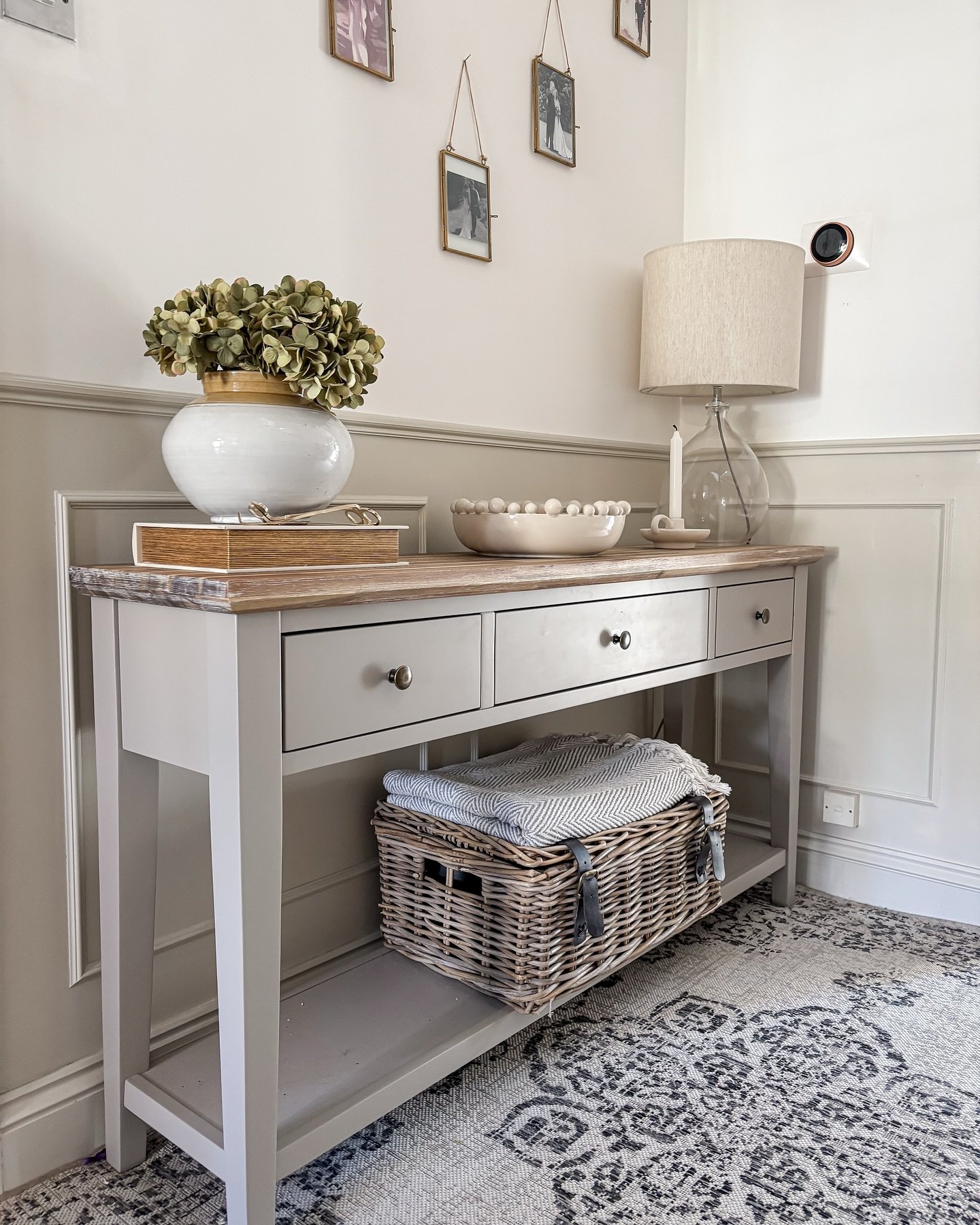 Grey hallway table with wicker hamper and dried flowers