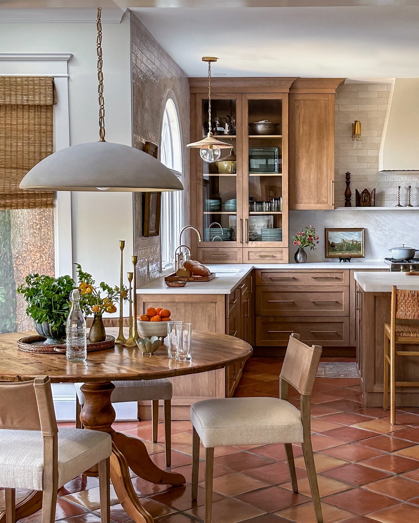 Round wooden kitchen table with a single pedestal base and upholstered chairs