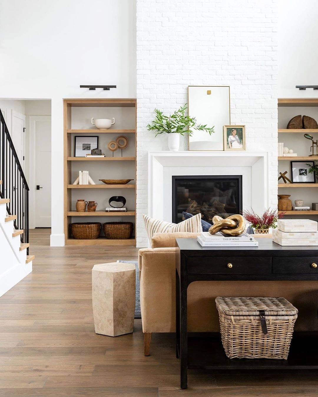Recessed wooden built-in shelves flanking a fireplace with neutral decor and baskets