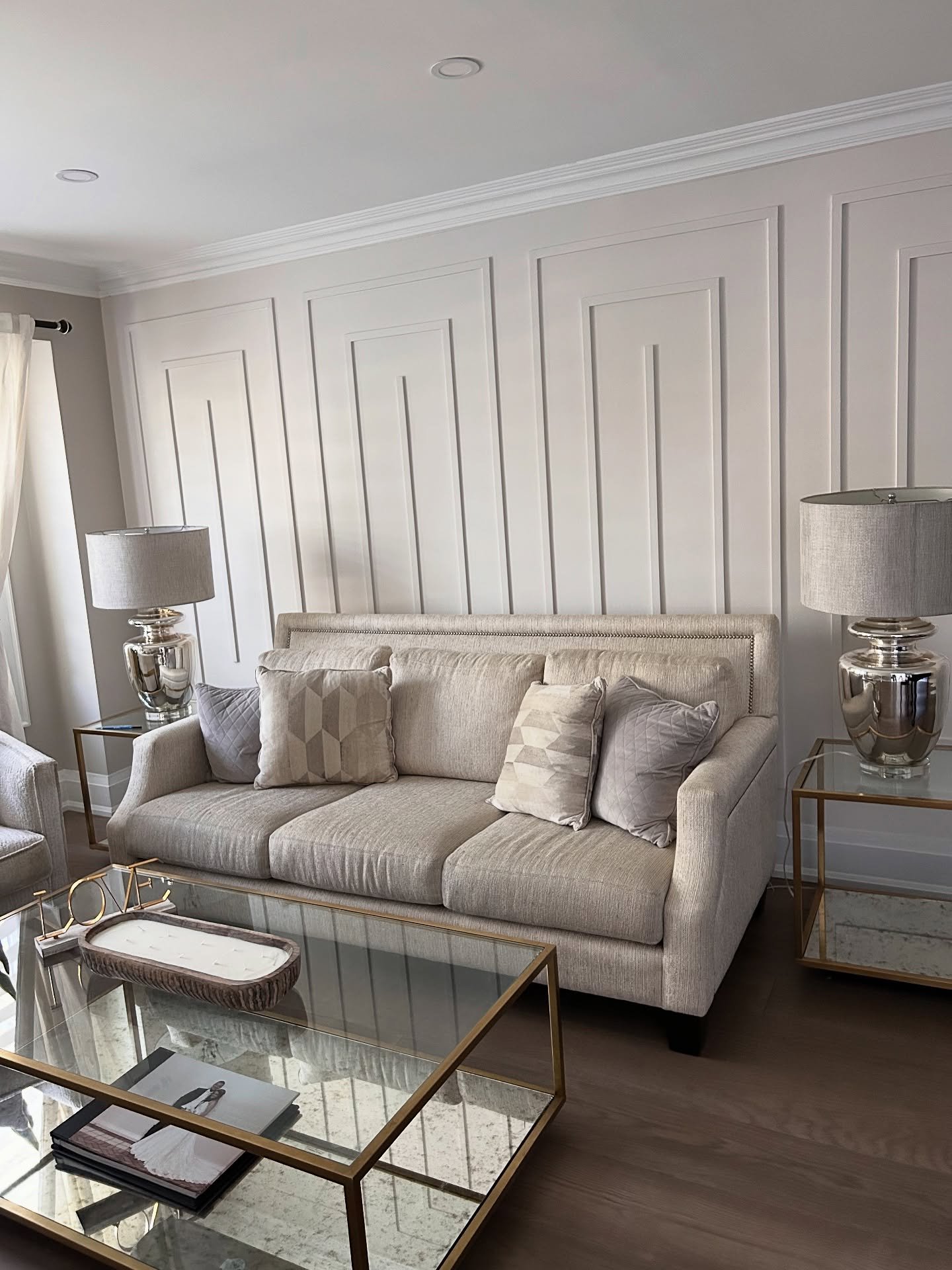 Beige living room featuring a geometric paneled accent wall behind a sofa
