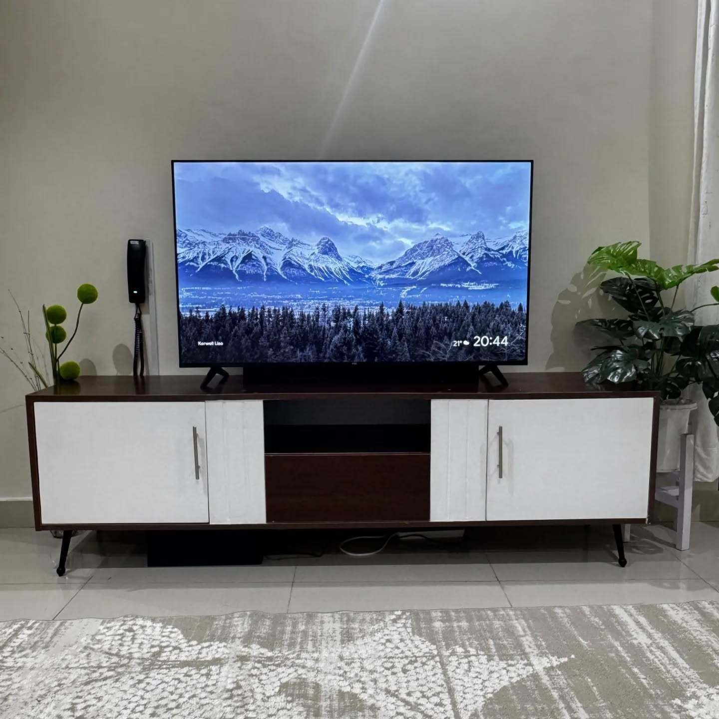 Dark wood TV stand with white cabinet doors and tapered legs