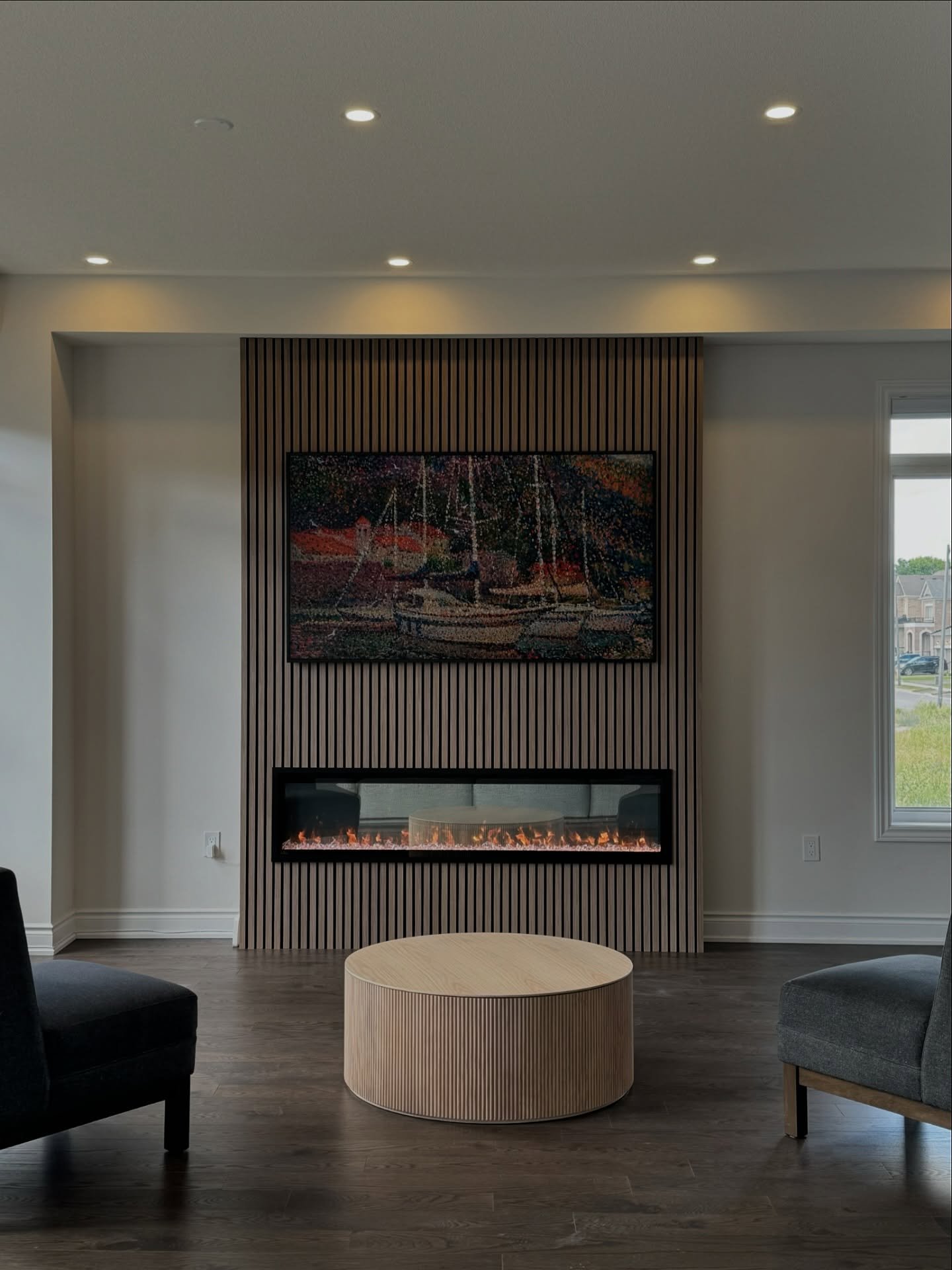 Minimalist living room featuring a linear fireplace and a TV mounted on a vertical light wood slat accent wall.
