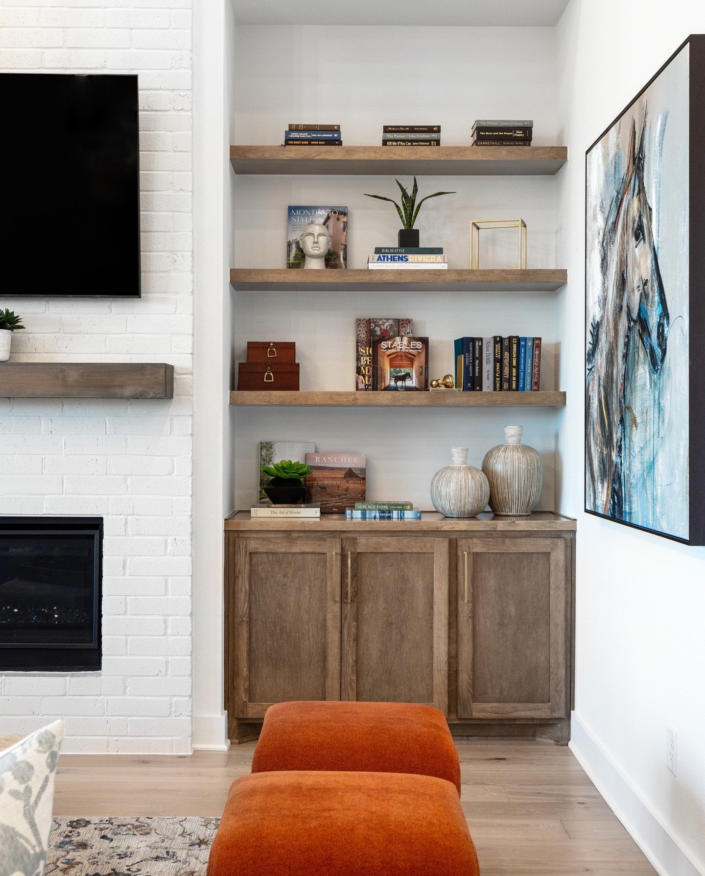 Floating wooden shelves and lower cabinets built into a white living room niche