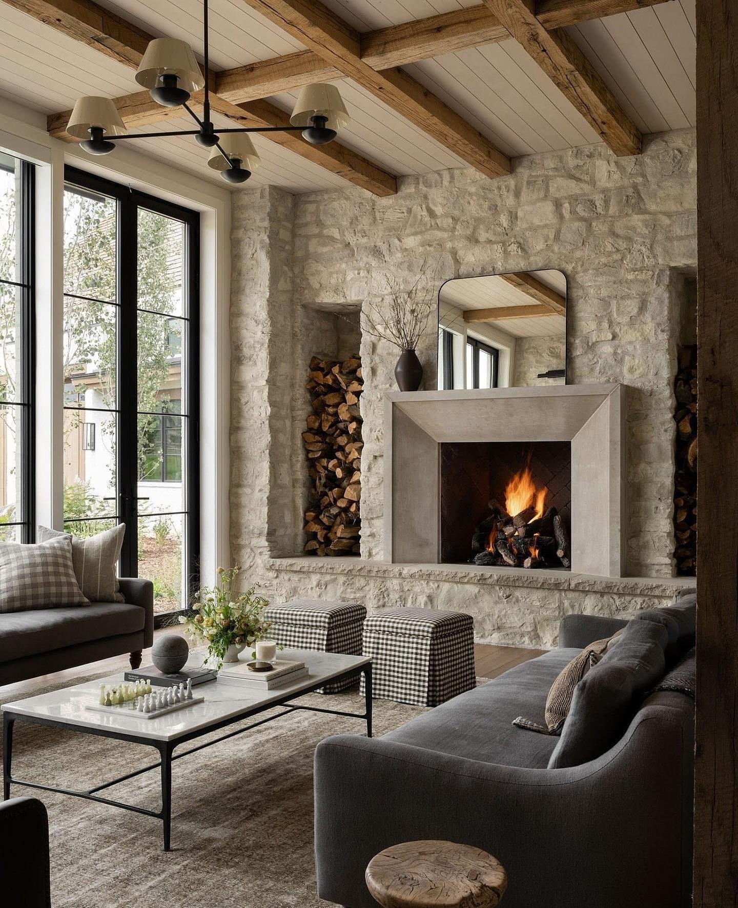 A contemporary living room featuring a floor-to-ceiling white stone fireplace with a smooth, light grey concrete or cast stone firebox surround, flanked by vertical wood storage niches.