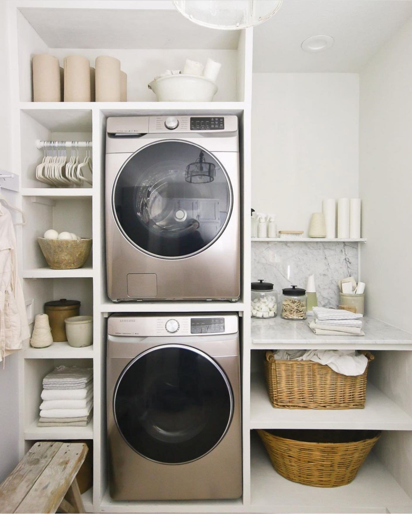 White built-in laundry shelves surrounding stacked machines with cubbies and under-counter storage