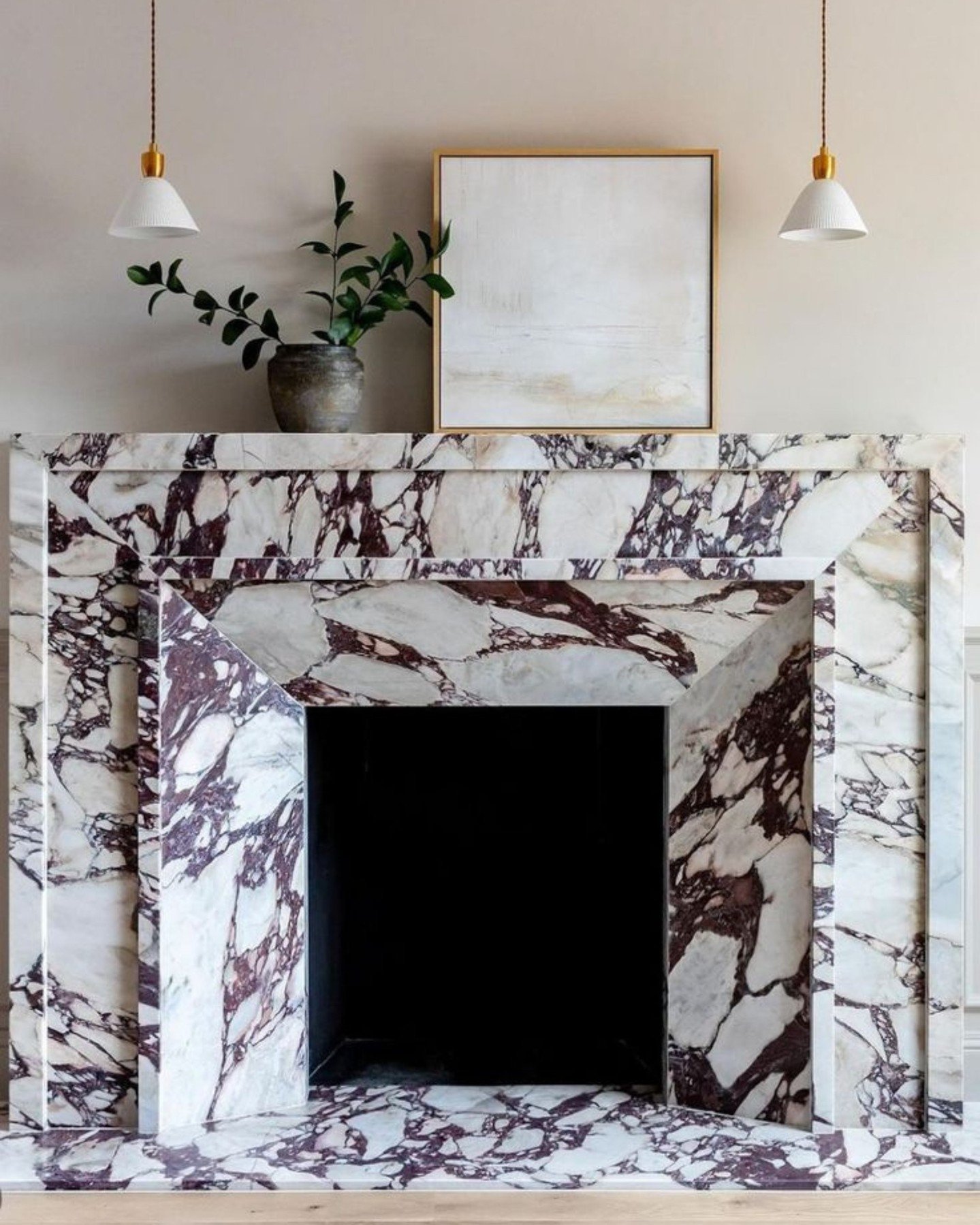 A dramatic fireplace surround made entirely of Calacatta Viola marble featuring intense, thick purple-brown veining against a white background.