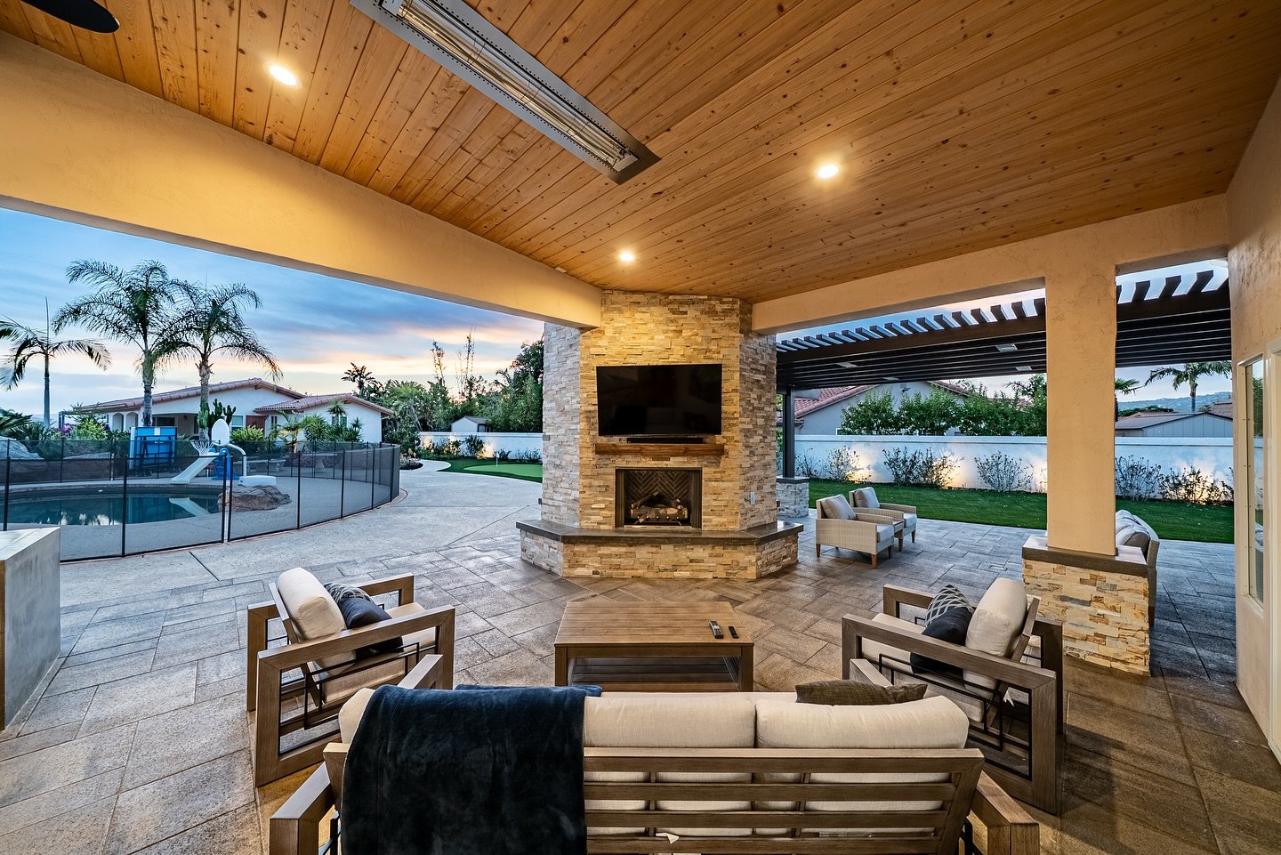 Multi-toned stacked stone fireplace built into a corner pillar on a covered outdoor patio.