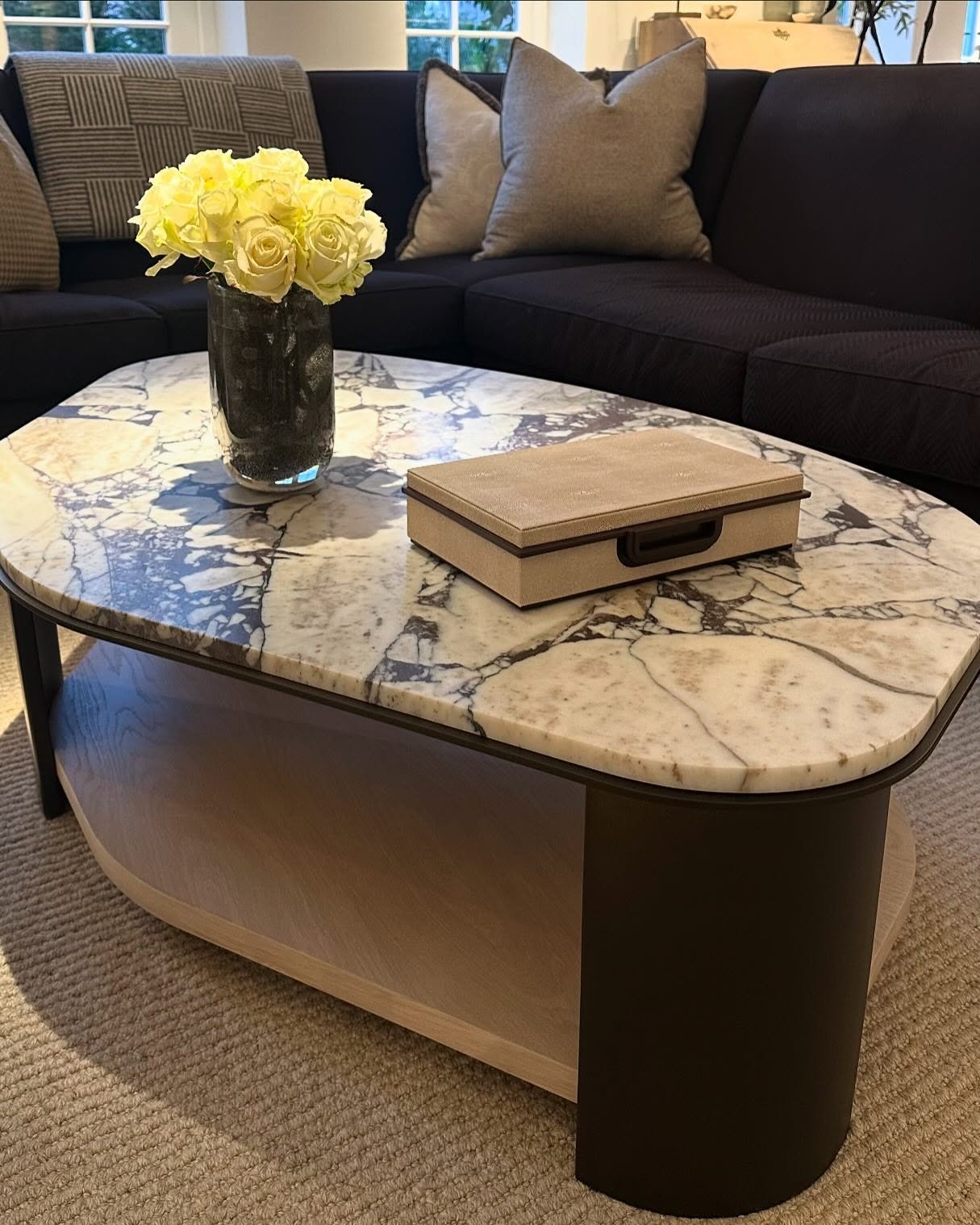 Oval marble top coffee table with lower shelf and dark metal legs