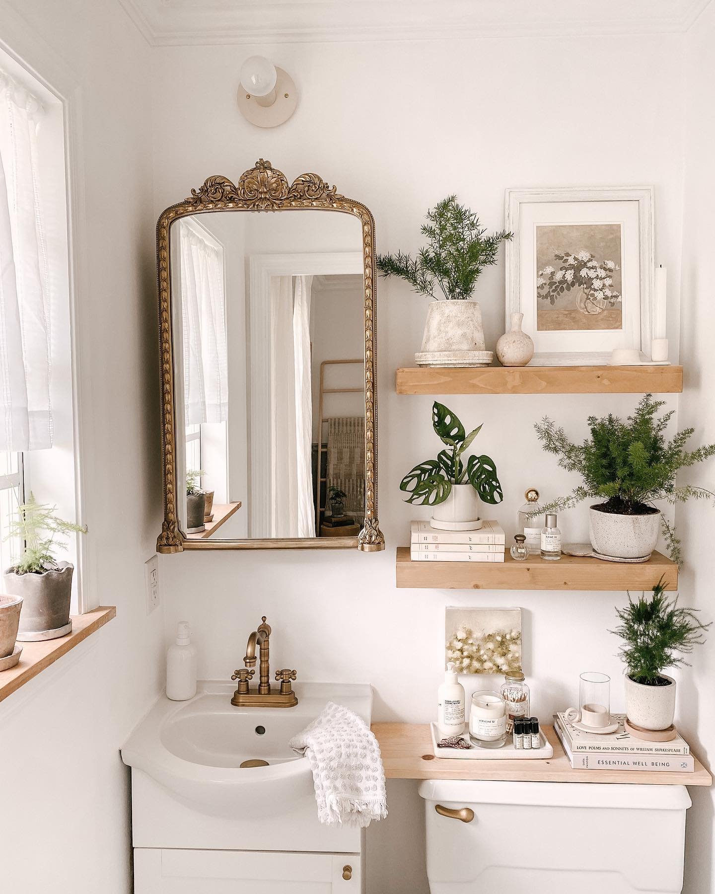Light pine wood floating shelves arranged next to an ornate mirror