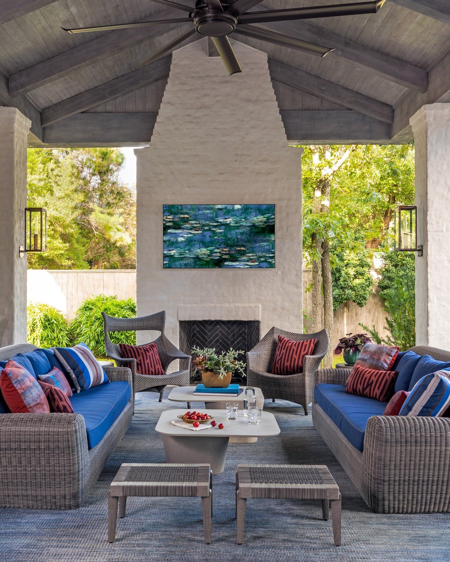 A very tall outdoor fireplace finished in white stucco with a peaked chimney on a covered patio.