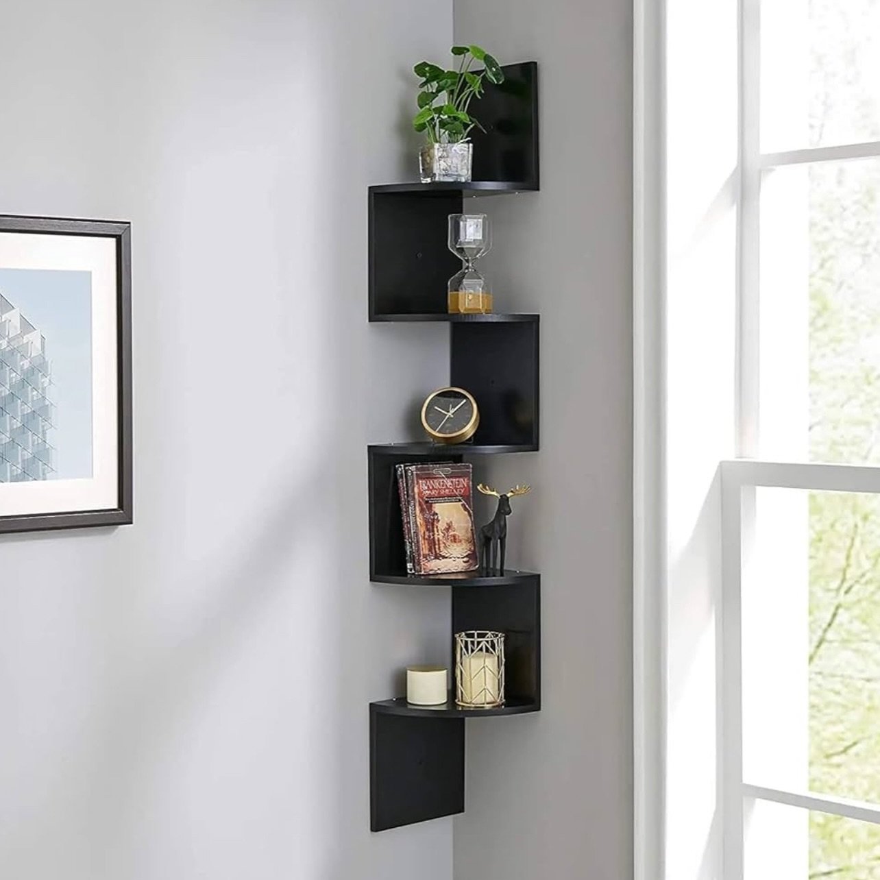 Tall black zig-zag corner floating shelf unit with rounded edges on a grey wall.
